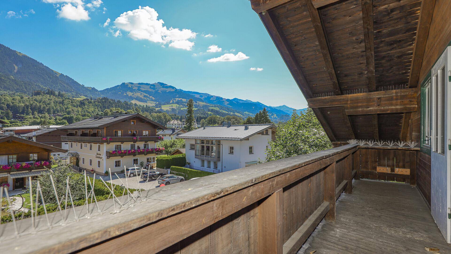 Geräumiger Holzbalkon mit Blick auf die grünen Berge und die umliegende Bebauung.