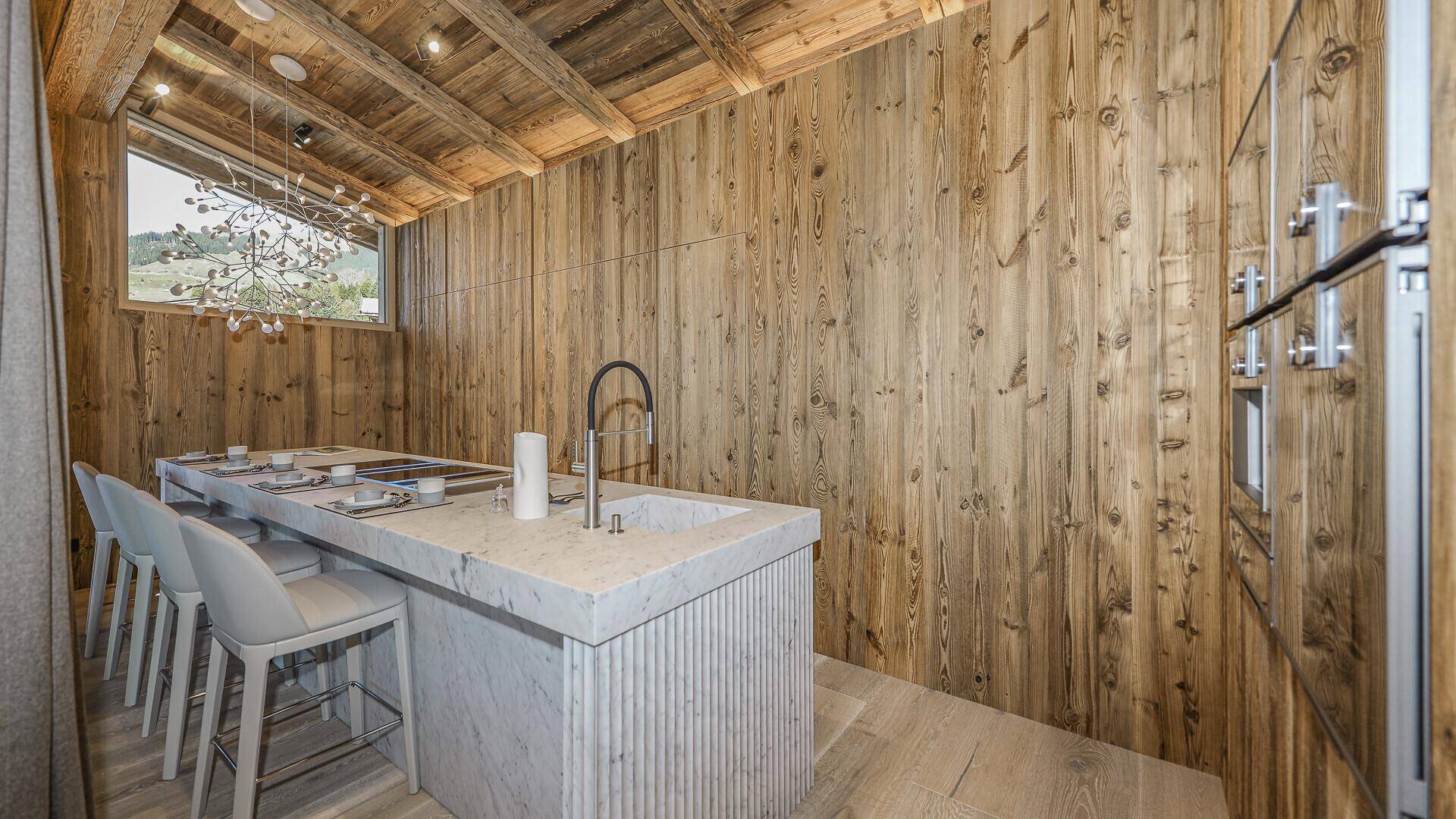 Moderne Küche mit Holzwänden, Marmorinsel und integrierten Geräten in hellem Design.