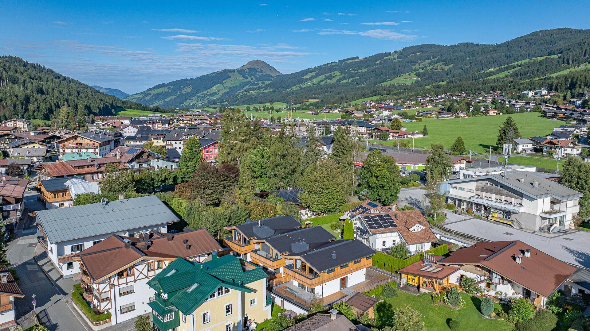 Panoramablick auf ein malerisches Dorf in den Bergen mit grünen Wiesen und Wäldern.