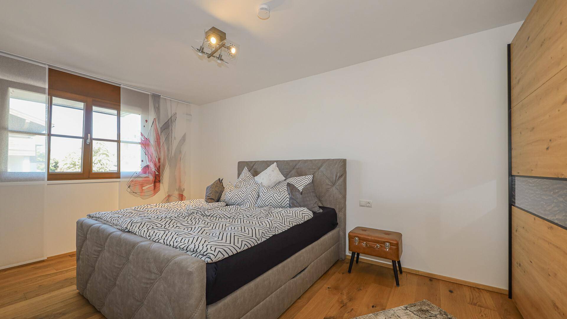 Helles Schlafzimmer mit Doppelbett, Holzboden und modernem Kleiderschrank.
