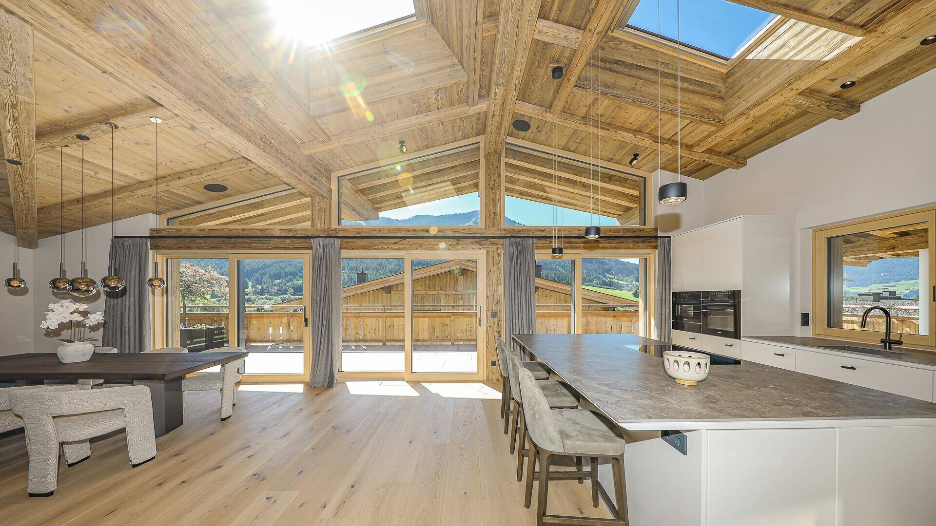 Großzügiger offener Wohnbereich mit Küche, Essbereich und Zugang zur Terrasse, lichtdurchflutet.