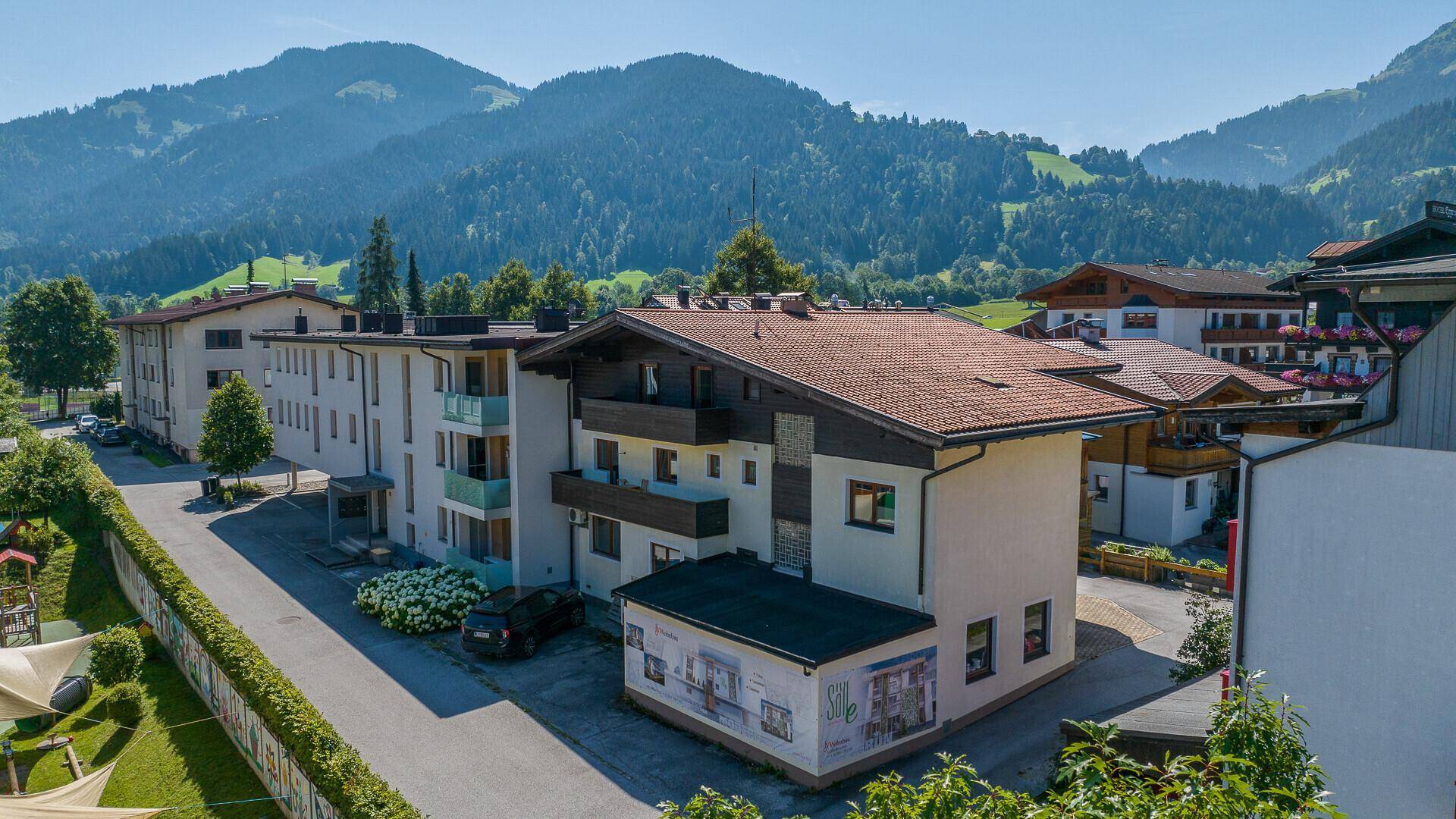 Bestehendes Gebäude in alpiner Umgebung mit traditioneller Architektur und Balkonen.