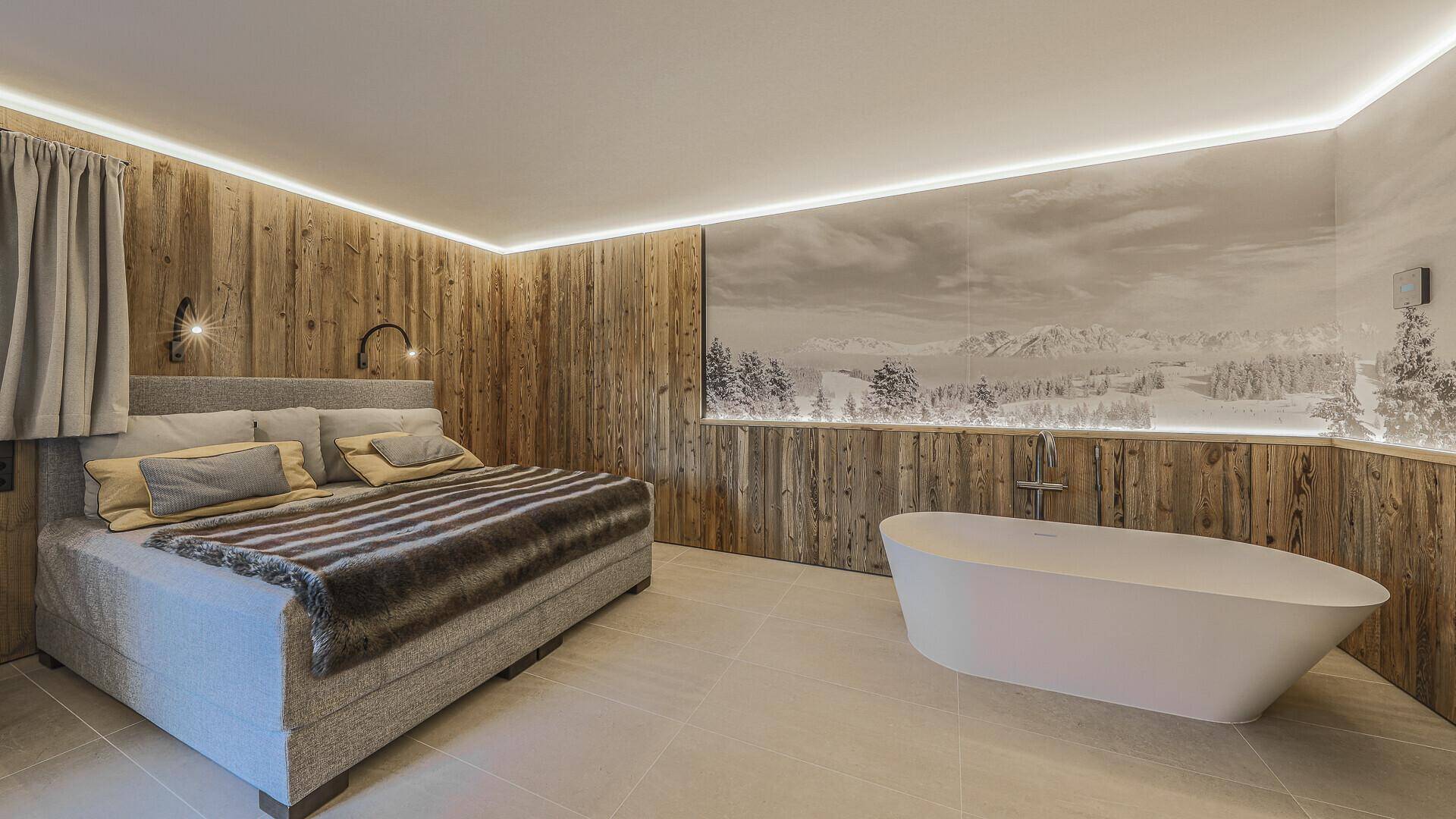 Geräumiges Schlafzimmer mit freistehender Badewanne, Holzwänden und Bergpanorama-Wandbild.