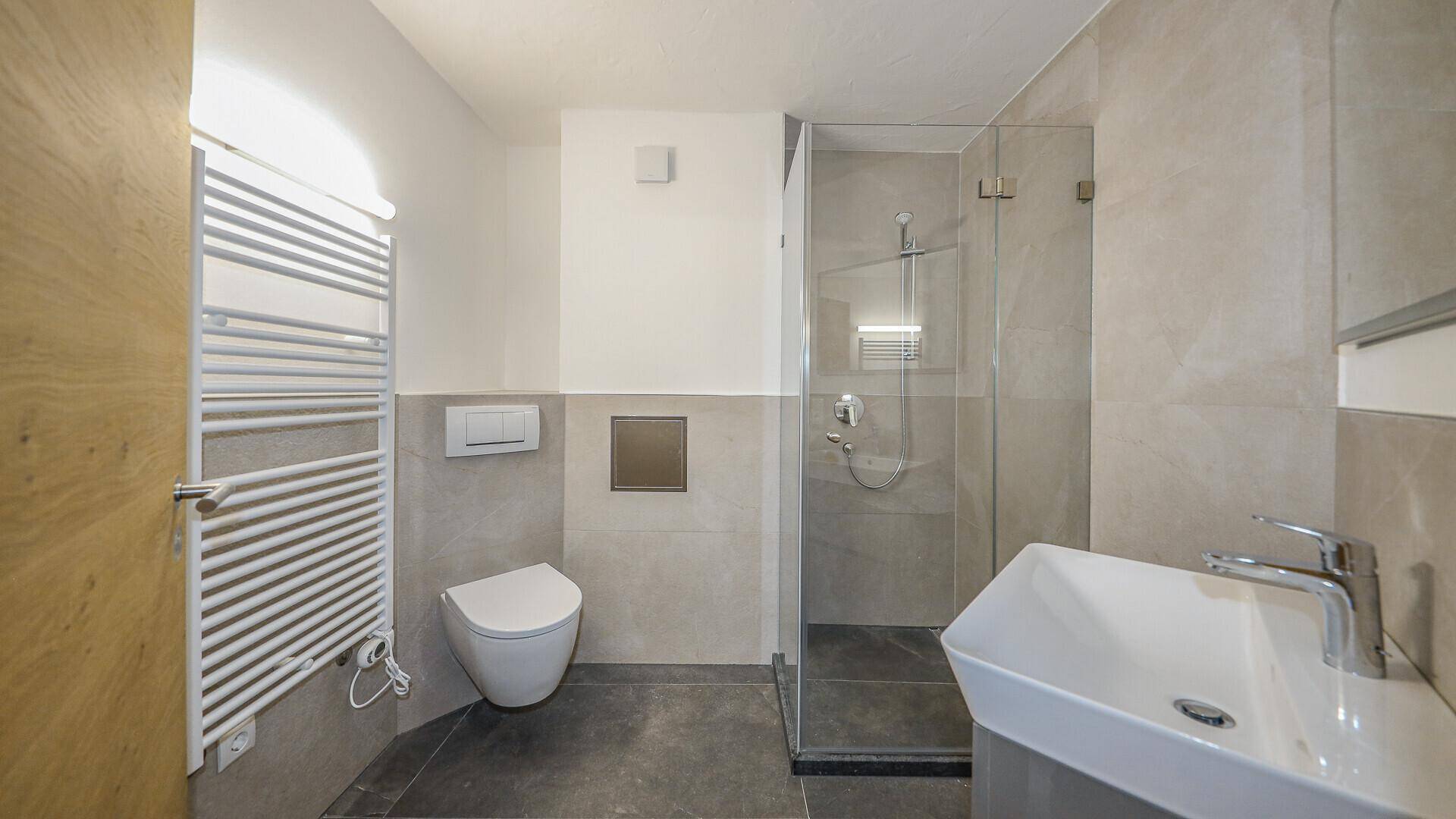 Modernes Badezimmer mit begehbarer Dusche, Wand-WC und beheiztem Handtuchhalter.