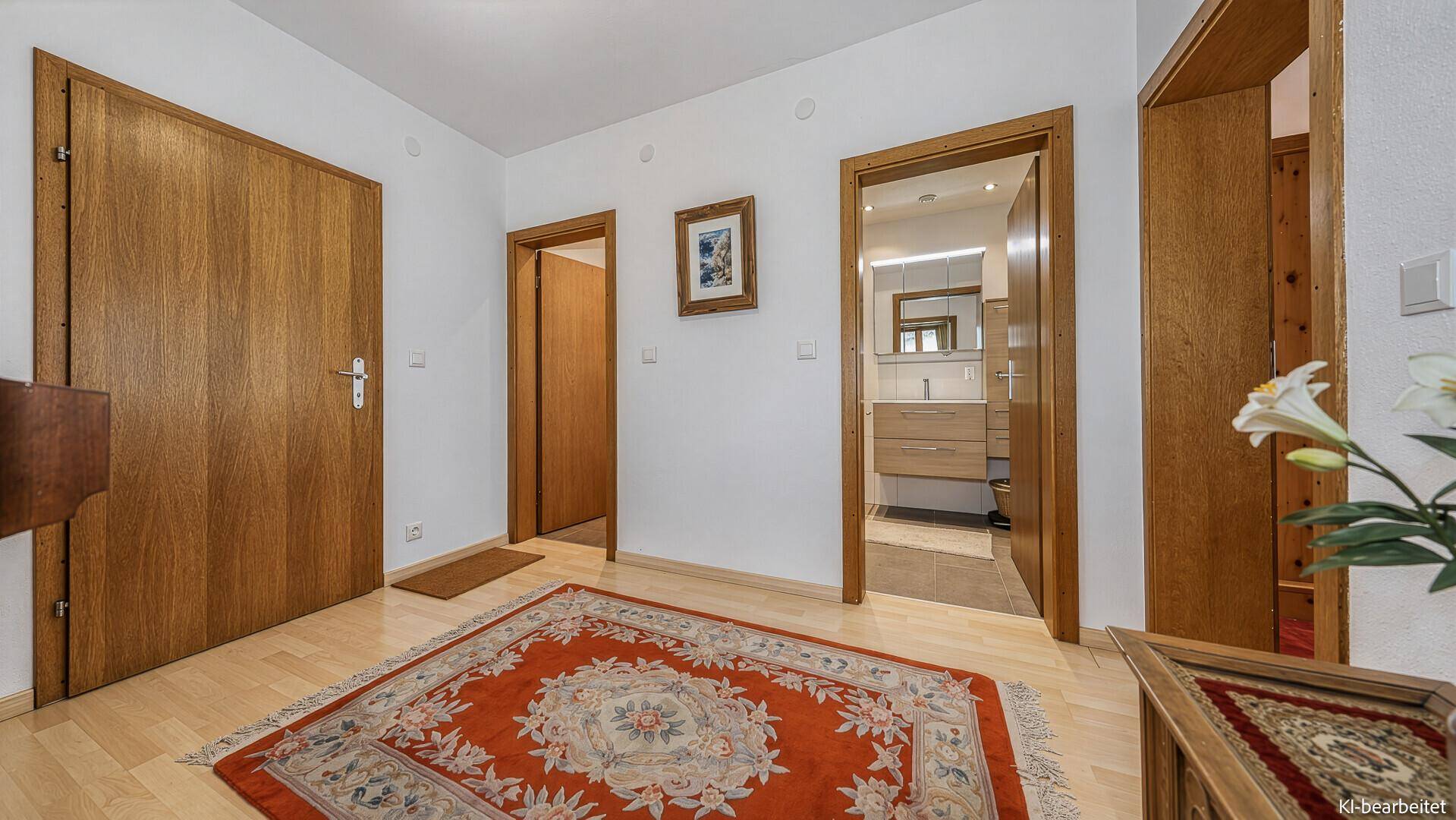 Flur mit Holztüren, traditionellem Teppich und Blick in ein Badezimmer.