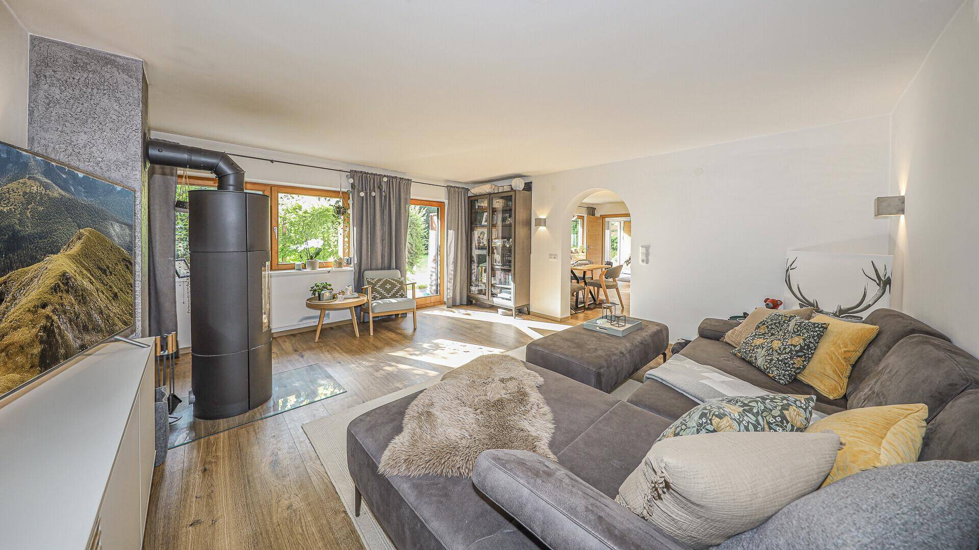 Geräumiges Wohnzimmer mit modernem Kaminofen, großem Sofa und Blick in den angrenzenden Essbereich.