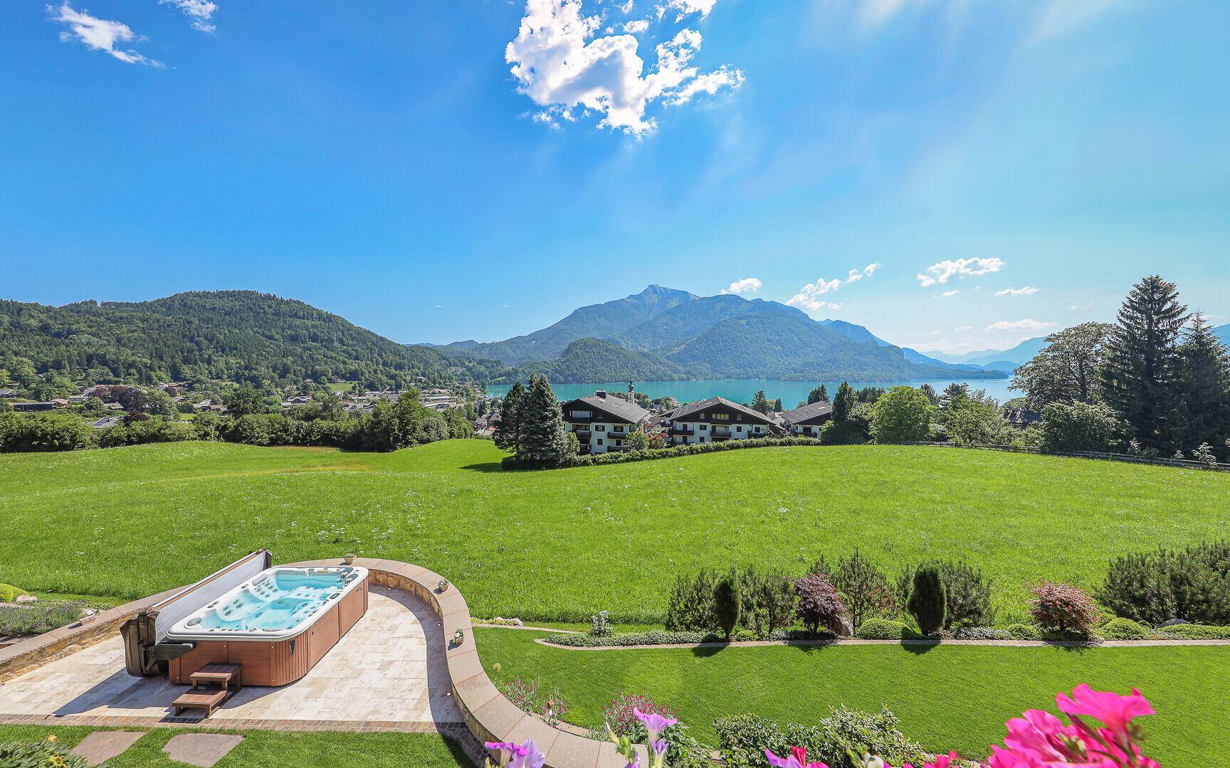 Whirlpool im Freien auf einer Terrasse mit Panoramablick auf den See und die Berge.