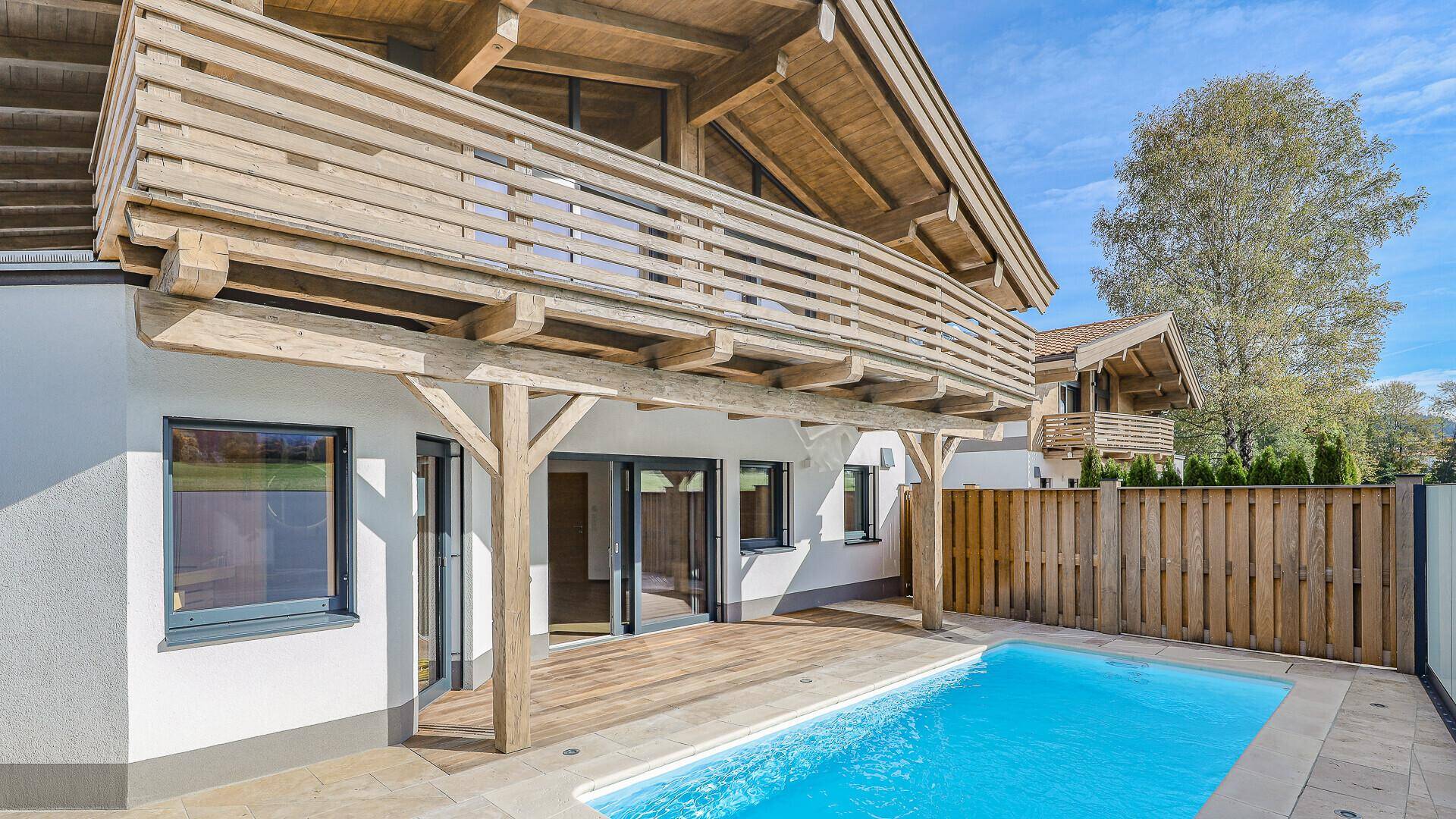 Außenbereich mit privatem Pool, Holzterrasse und Balkon im Obergeschoss.