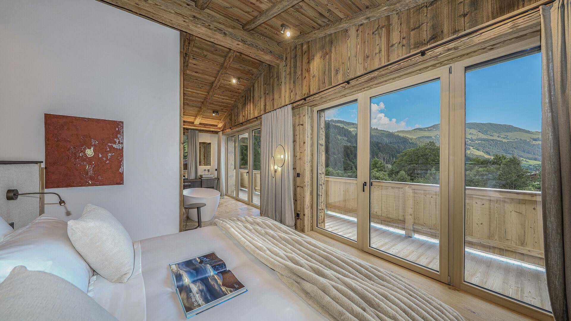 Luxuriöses Schlafzimmer mit Holzwänden, großem Bett und offenem Zugang zum Badezimmer.