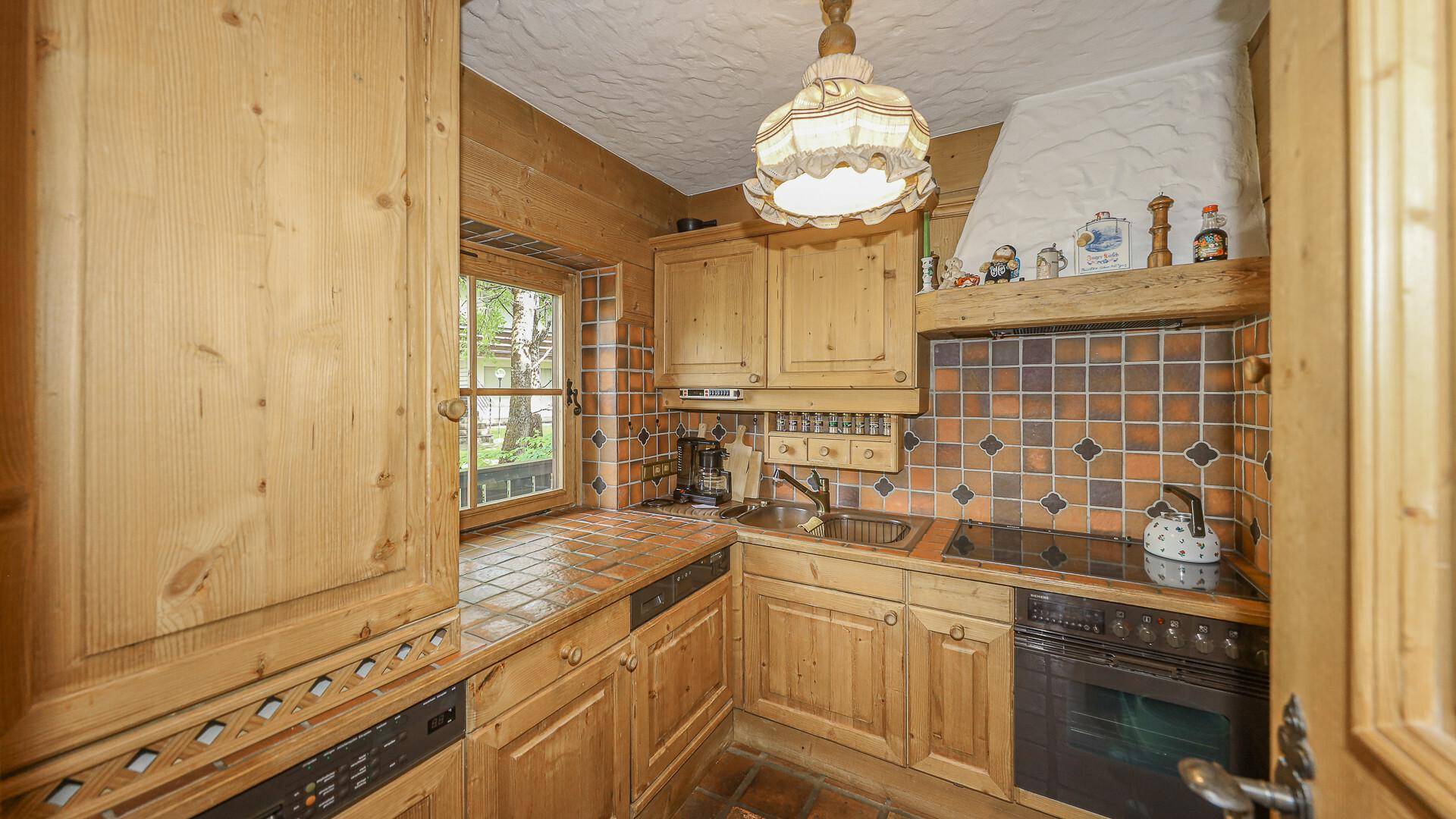 Rustikale Küche mit Holzschränken, Fliesenrückwand und funktionalen integrierten Geräten.