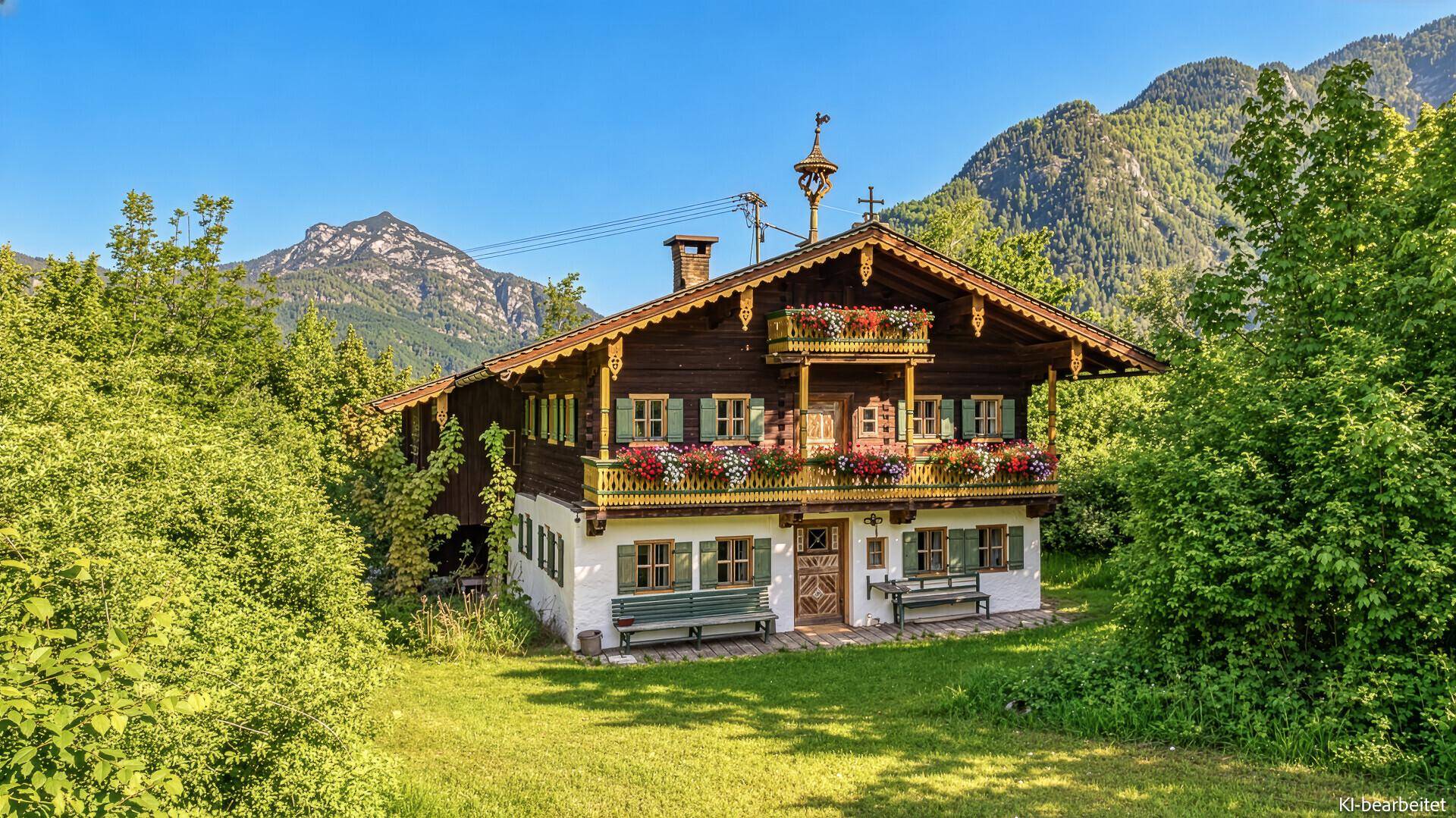 Traditionelles bayerisches Chalet mit Holzbalkonen und Blumenkästen vor einer beeindruckenden Bergkulisse.