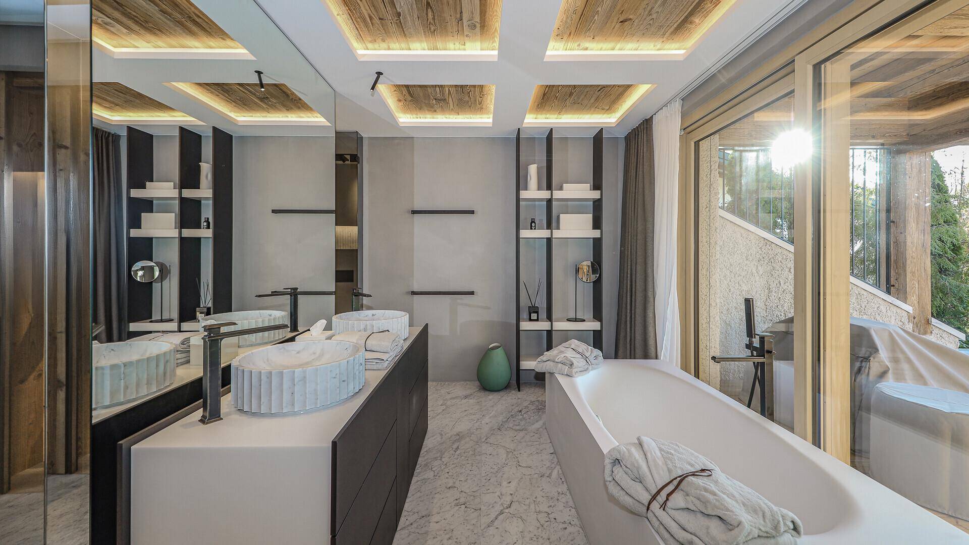 Luxuriöses Badezimmer mit freistehender Badewanne, Doppelwaschbecken und großem Spiegel.