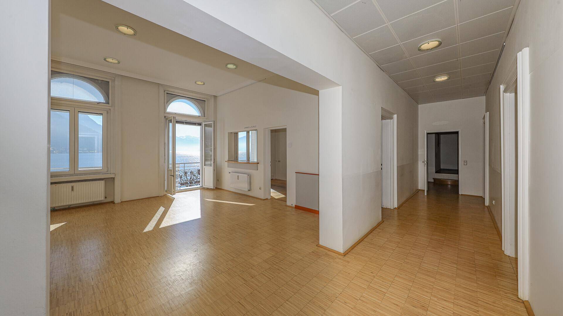 Großer, heller Wohnraum mit Parkettboden und angrenzendem Flur, beide mit Seeblick.