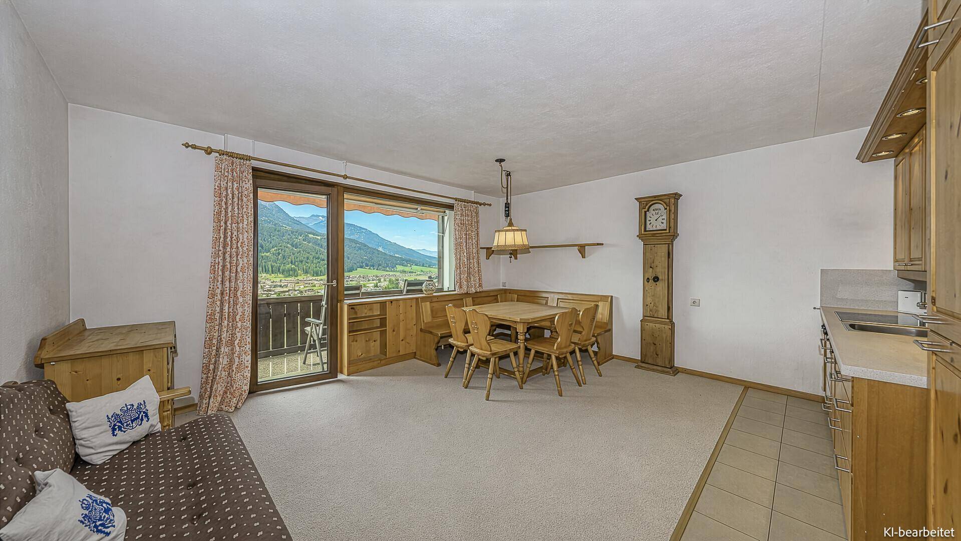 Traditioneller Wohn-Essbereich mit rustikaler Holzküche und weitem Blick auf die Berglandschaft.