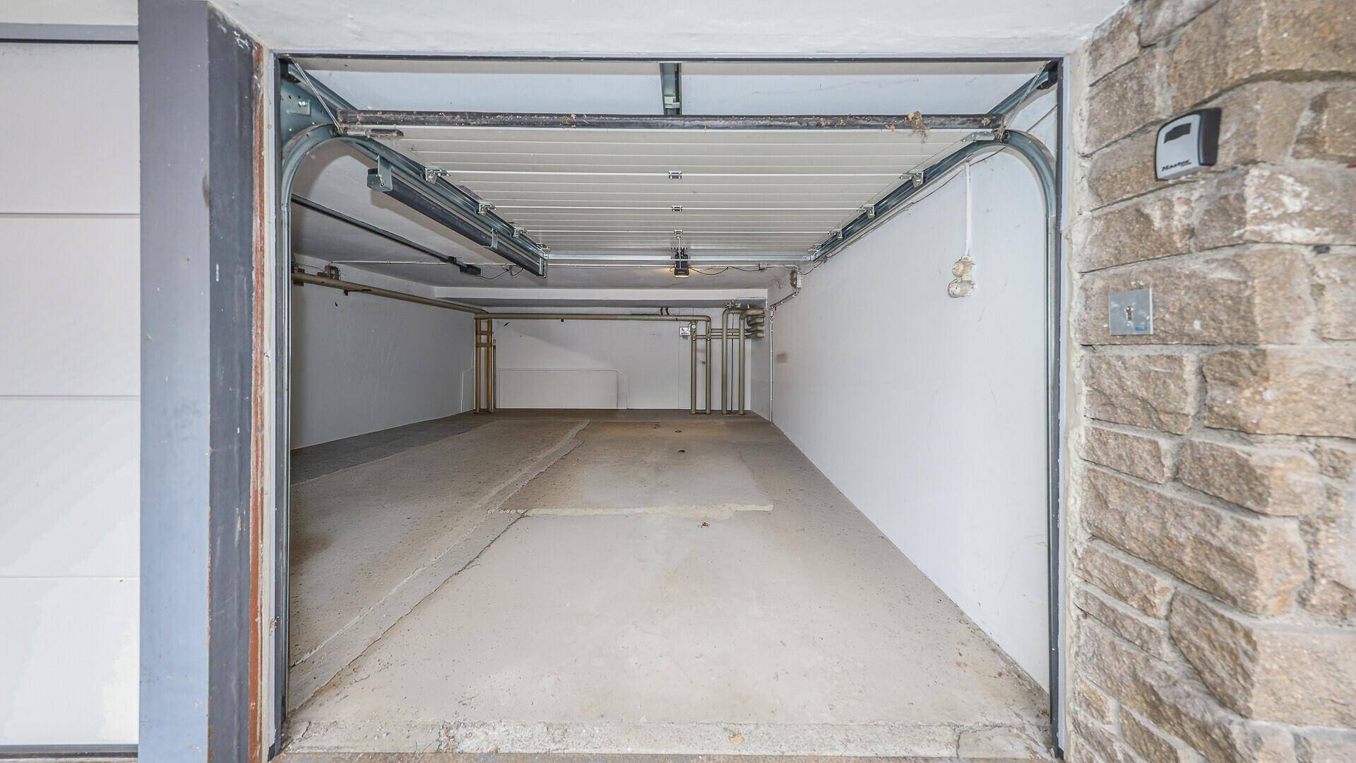 Leere Garage mit Betonboden und weiß gestrichenen Wänden, bereit zur Nutzung.