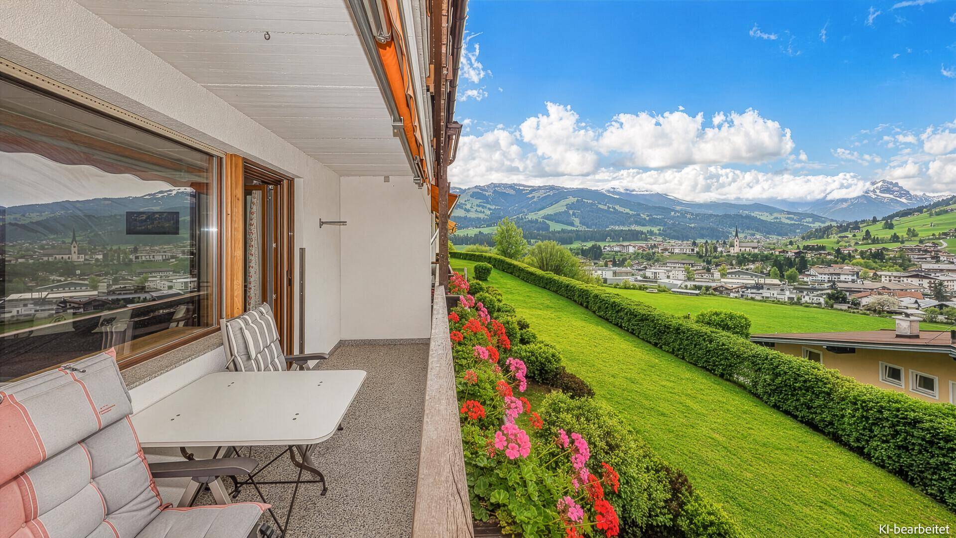Geräumiger Balkon mit Sitzgelegenheiten und weitem Blick über das Tal und die Berge.