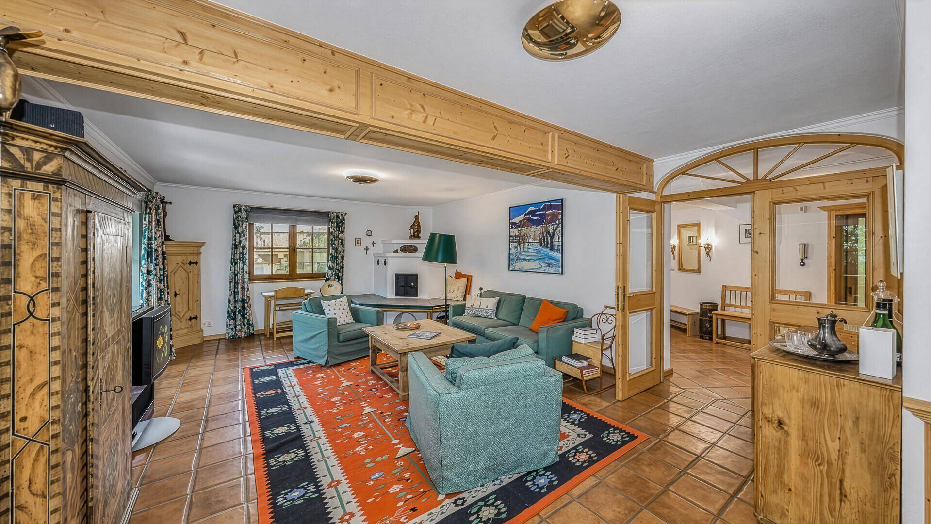 Geräumiges Wohnzimmer mit Kachelofen, rustikalen Möbeln und traditionellem Charme.