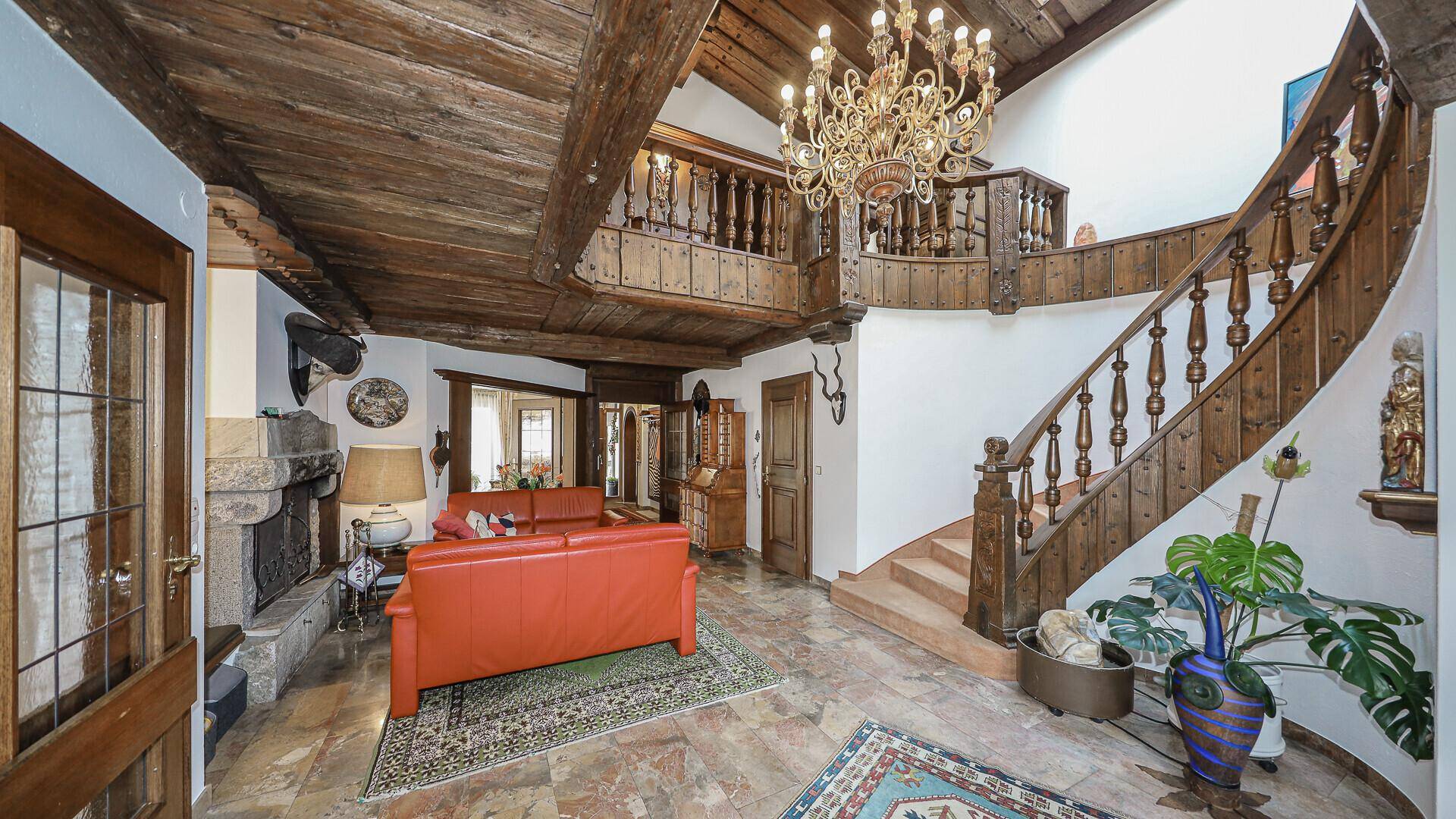Repräsentativer Eingangsbereich mit Holztreppe, Holzbalkendecke und Steinfliesenboden.