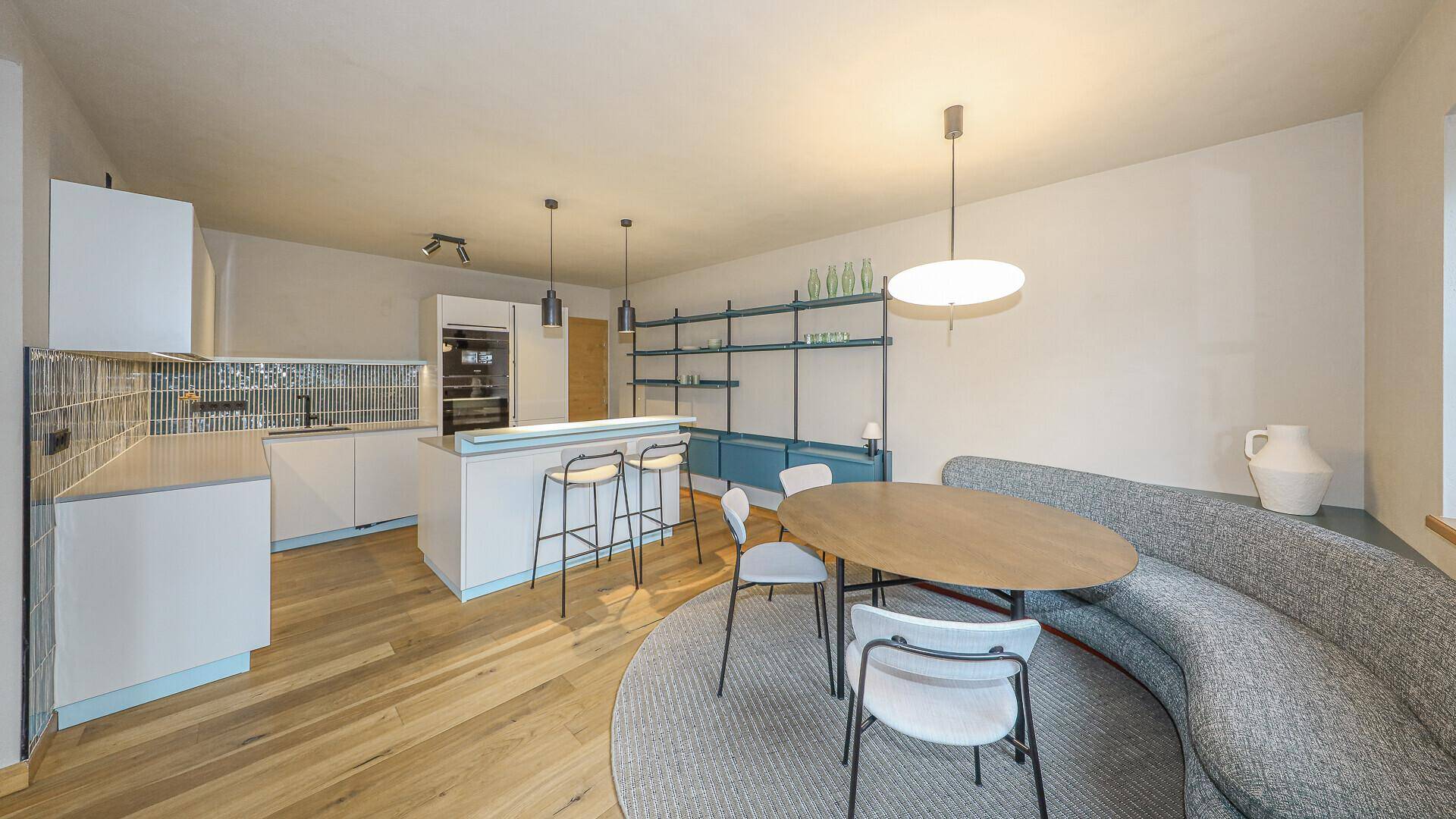 Moderne offene Küche mit Kochinsel, Essbereich und Holzboden in hellem, einladendem Design.