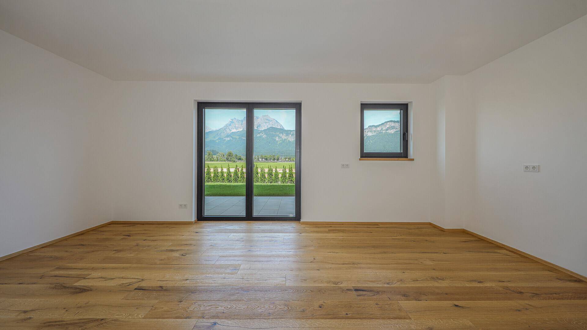 Geräumiger, unmöblierter Raum mit Holzboden und weitem Blick auf die Berge.