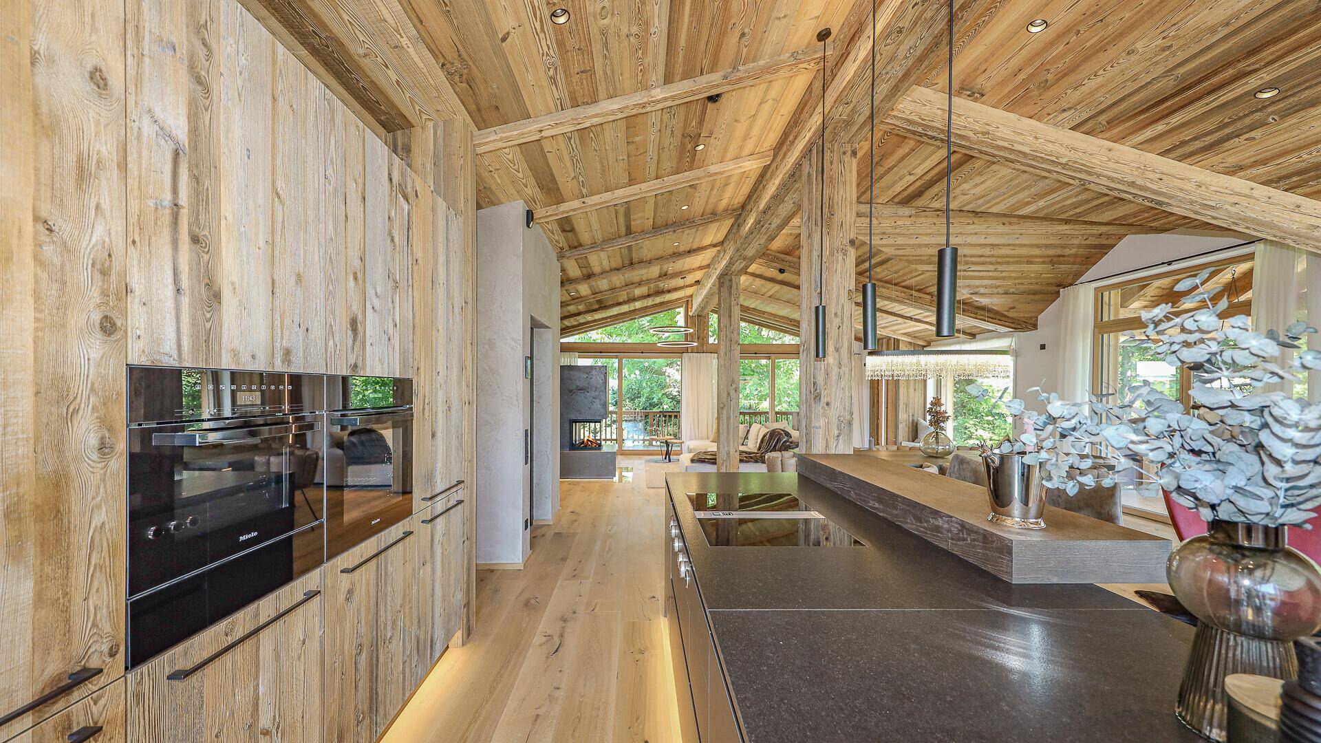 Offene Küche mit Holzwänden, dunkler Arbeitsplatte und hochwertigen Einbaugeräten.