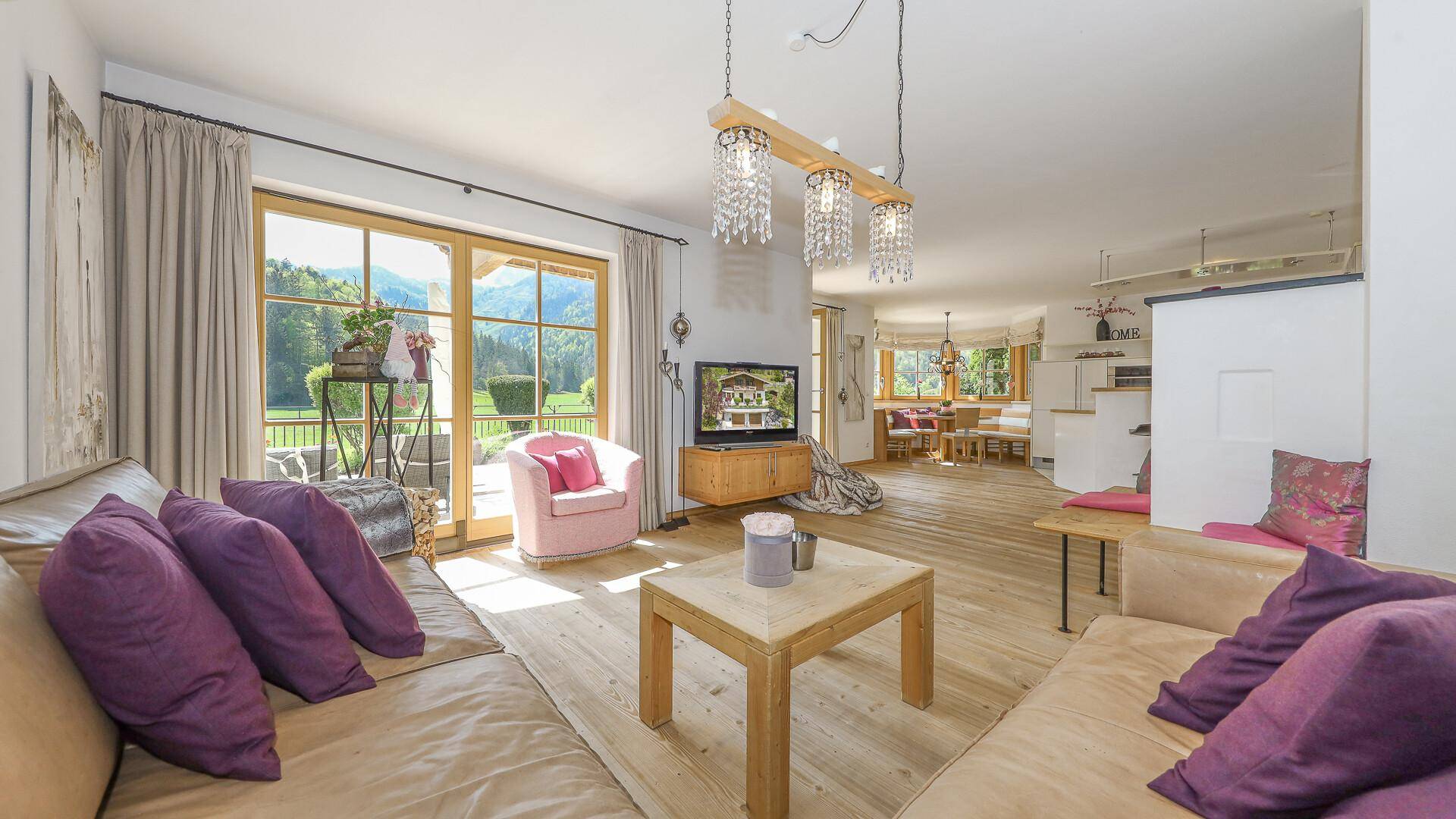 Helles Wohnzimmer mit großen Fenstern, Holzboden und direktem Zugang zur Terrasse mit Bergblick.