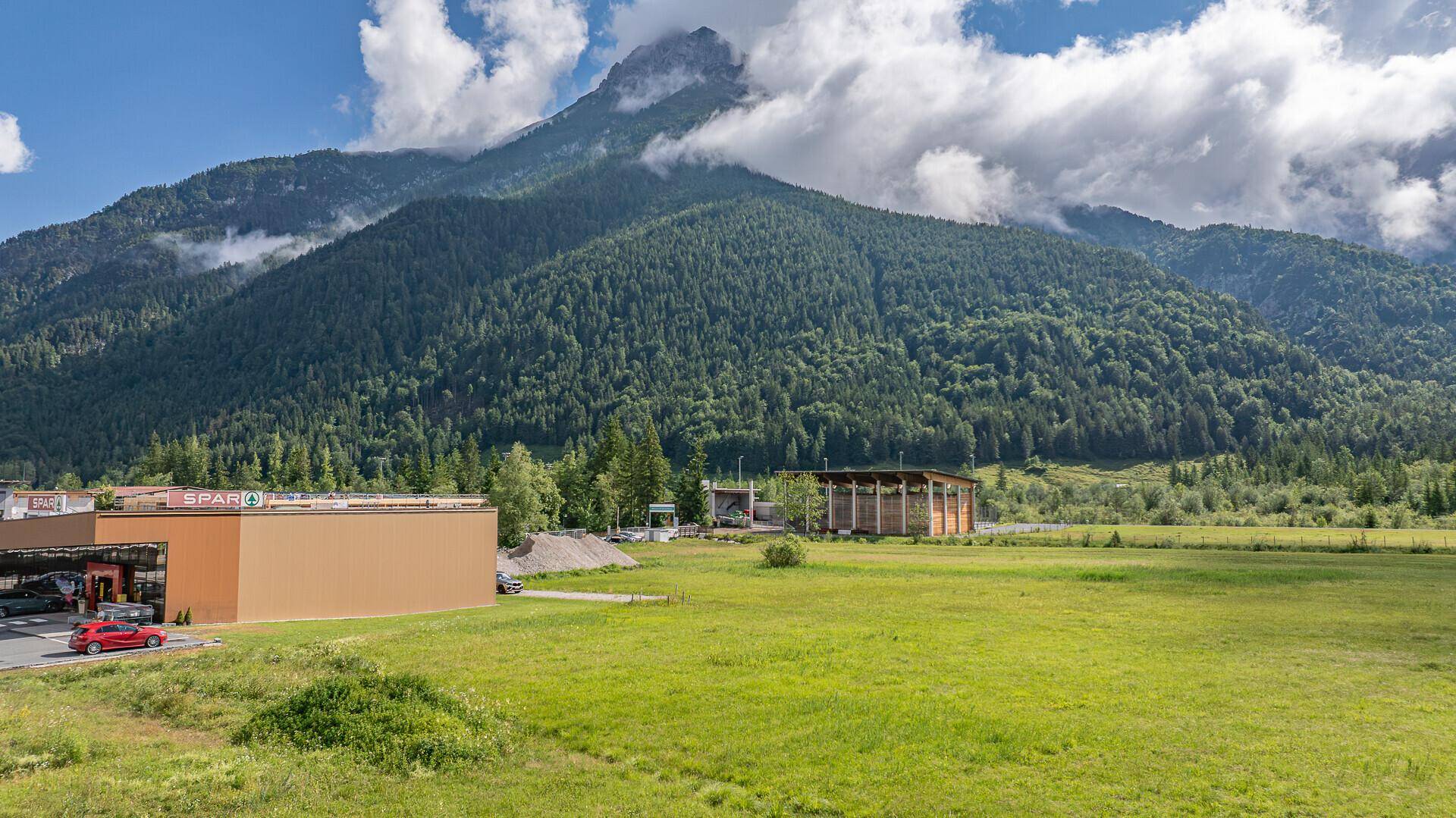 Weitläufiger Blick über ein Tal mit Geschäften und majestätischen Bergen im Hintergrund.