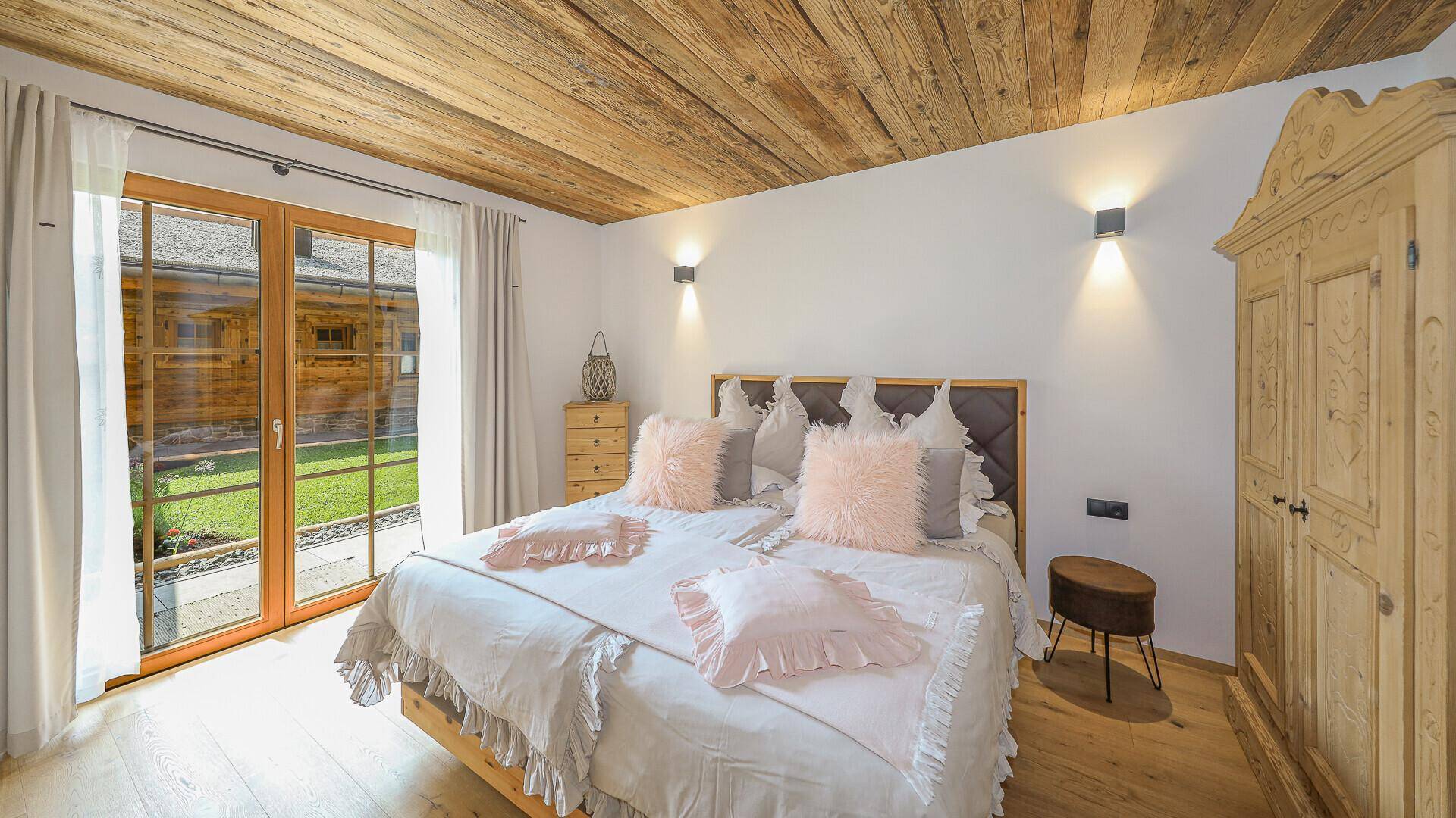 Gemütliches Schlafzimmer mit Holzbalkendecke, Doppelbett und Zugang zum Garten.