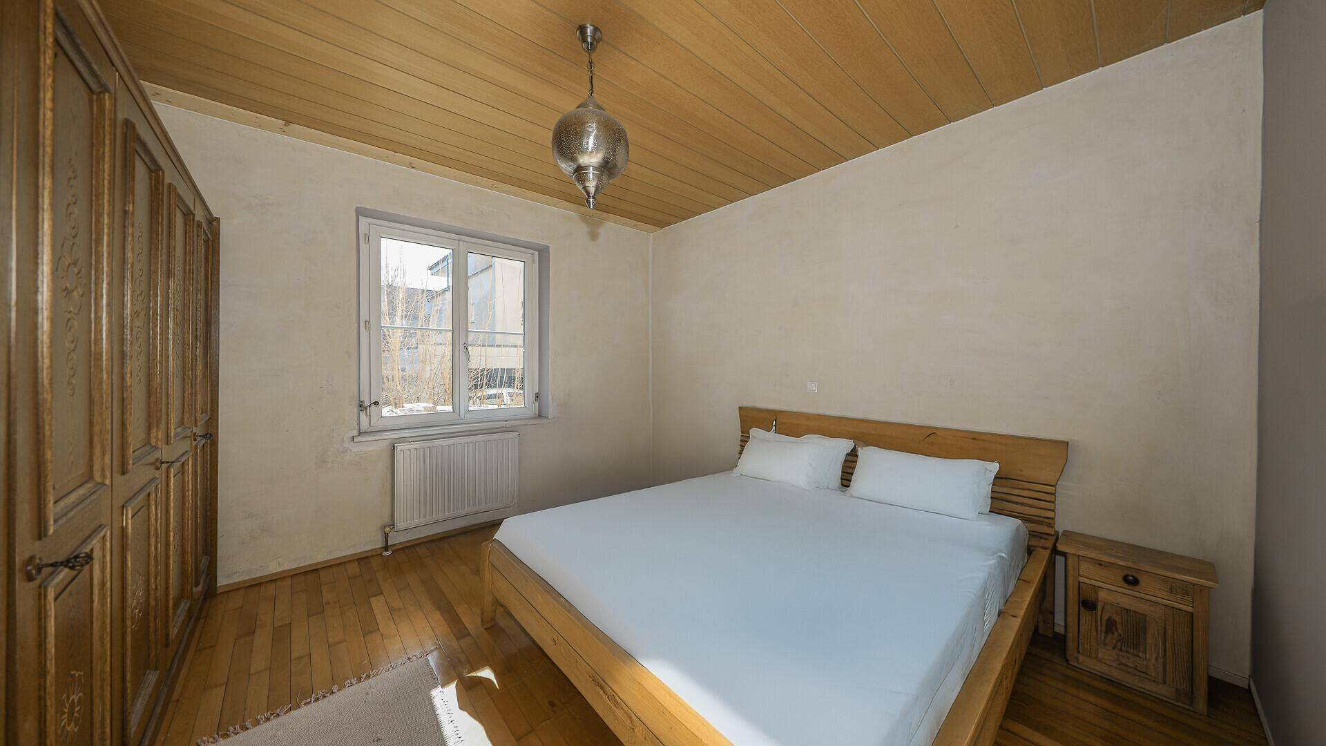 Schlafzimmer mit Holzbalkendecke, Parkettboden und traditionellem Kleiderschrank.