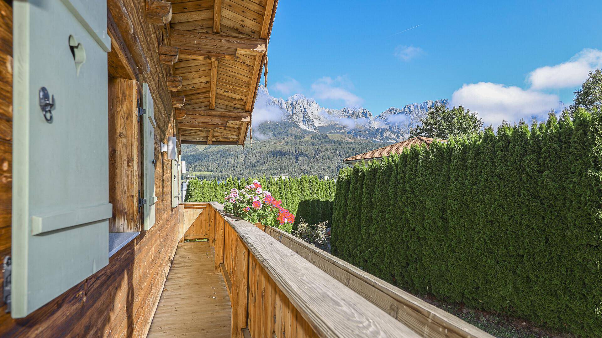Holzverkleideter Balkon mit Blumenkästen und beeindruckendem Bergblick.