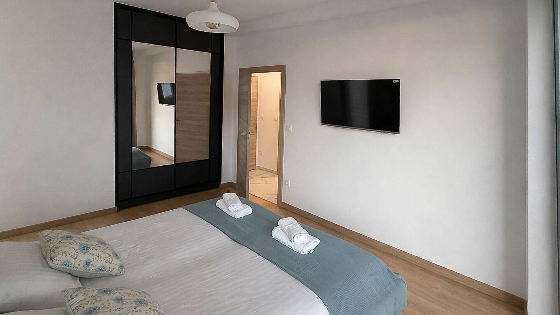 Komfortables Schlafzimmer mit Doppelbett, Holzboden und großem Spiegelschrank.