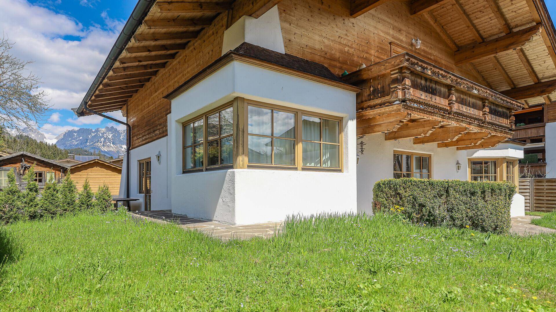 Seitenansicht des Chalets mit grünem Rasen und beeindruckendem Bergblick.