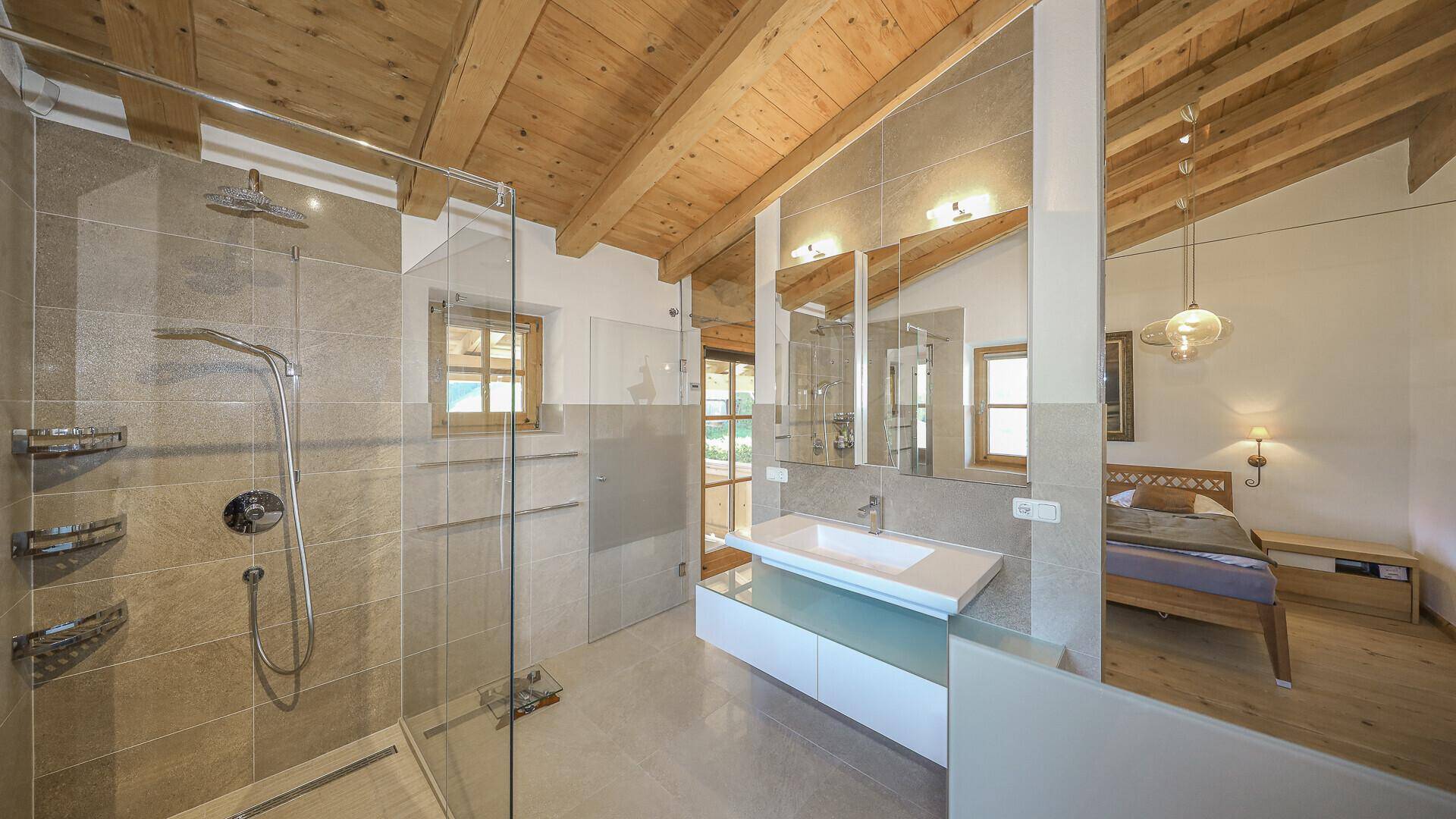 Elegantes Badezimmer mit großer Dusche, Doppelwaschbecken und direktem Zugang zum Schlafzimmer.