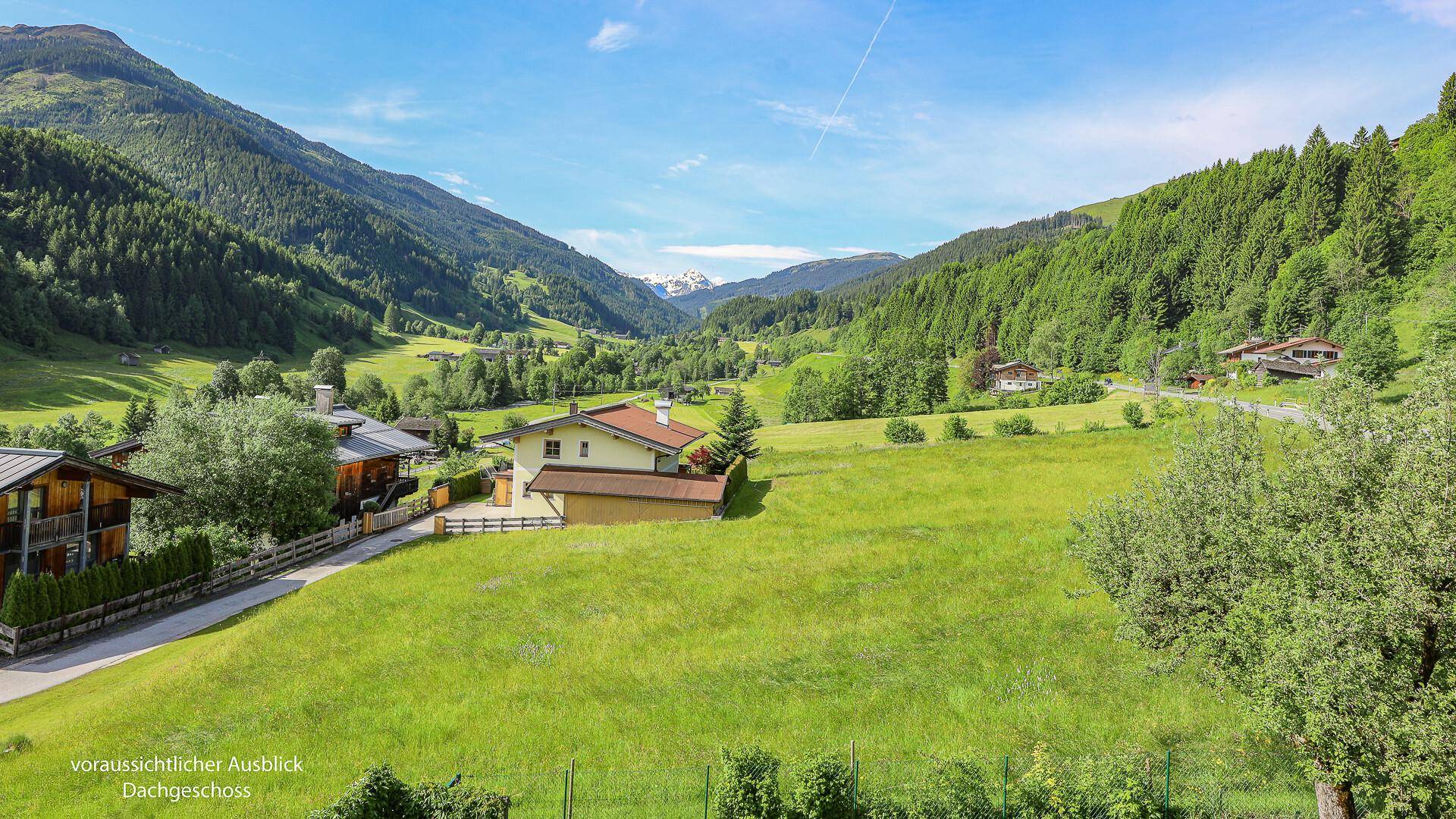 Idyllischer Blick auf ein Haus in einem weiten grünen Tal, umgeben von Wäldern und Bergen.