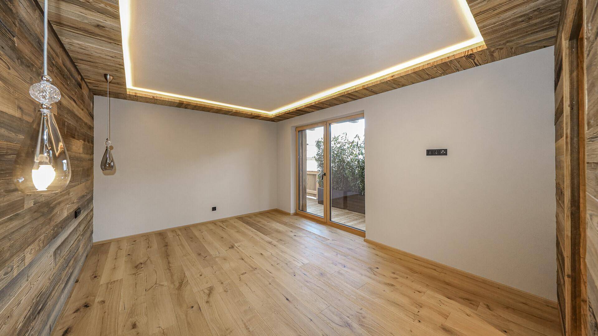 Schlafzimmer mit Holzwänden, Holzboden und Zugang zu einem Balkon oder einer Terrasse.