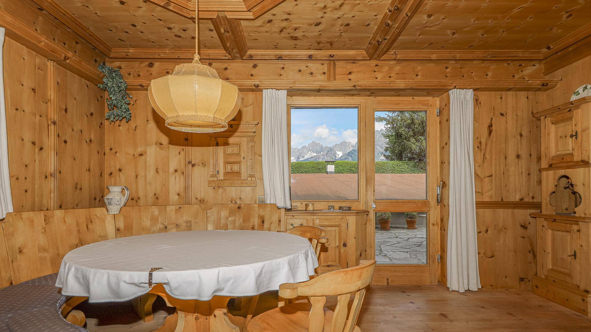 Gemütlicher Essbereich im alpinen Stil mit Holztäfelung, geschnitzten Möbeln und Blick auf die Berge.