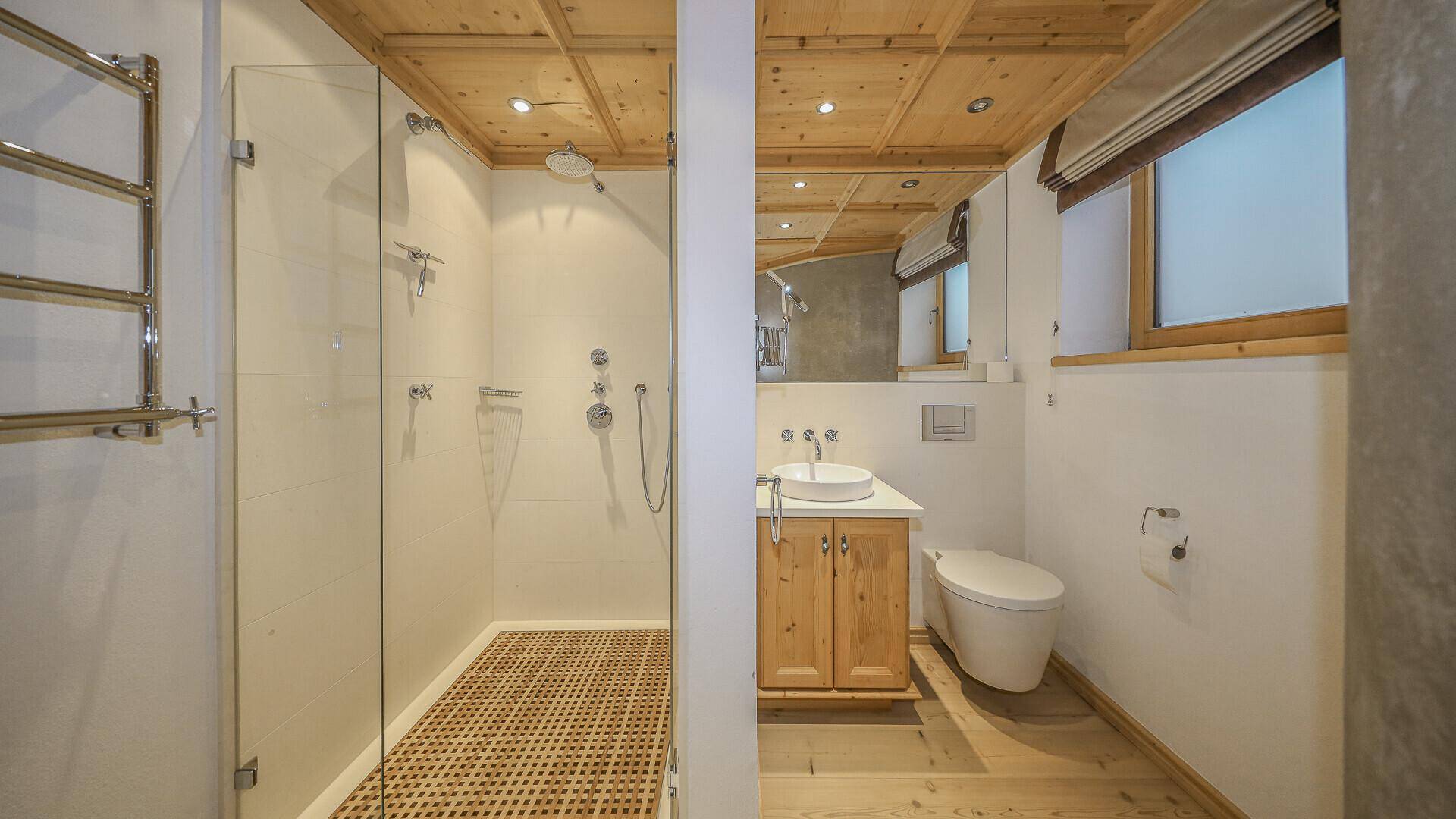 Modernes Badezimmer mit Dusche, Waschbecken und Holzbalkendecke.