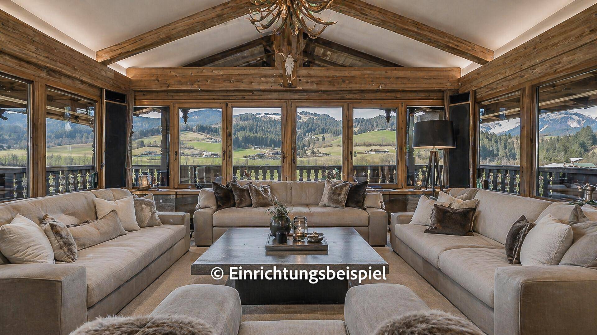 Modernisiertes Wohnzimmer mit bequemen Sofas, Holzbalkendecke und Panoramablick auf die Berge.