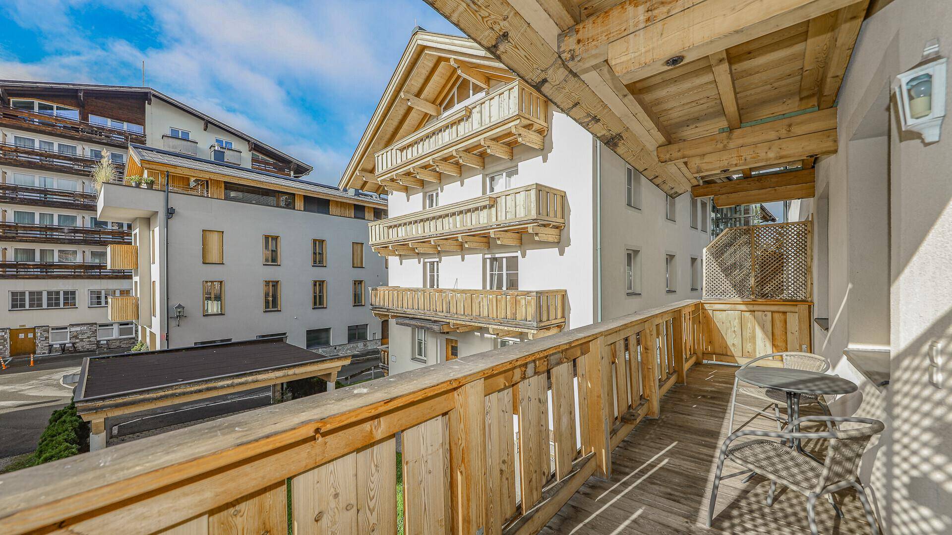 Geräumiger Holzbalkon mit Blick auf die Nachbargebäude und den blauen Himmel.