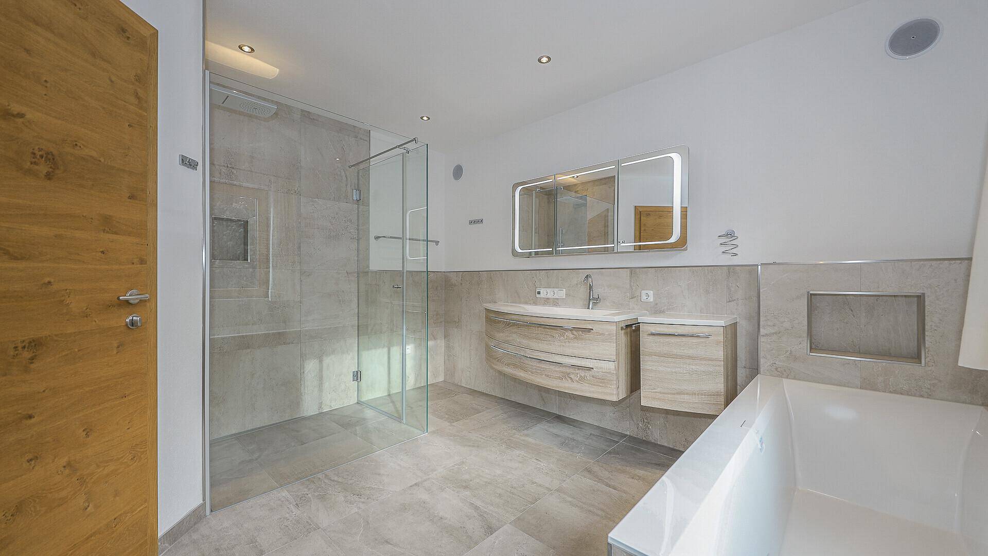 Elegantes Badezimmer mit begehbarer Dusche, schwebendem Waschtisch und großem Spiegelschrank.
