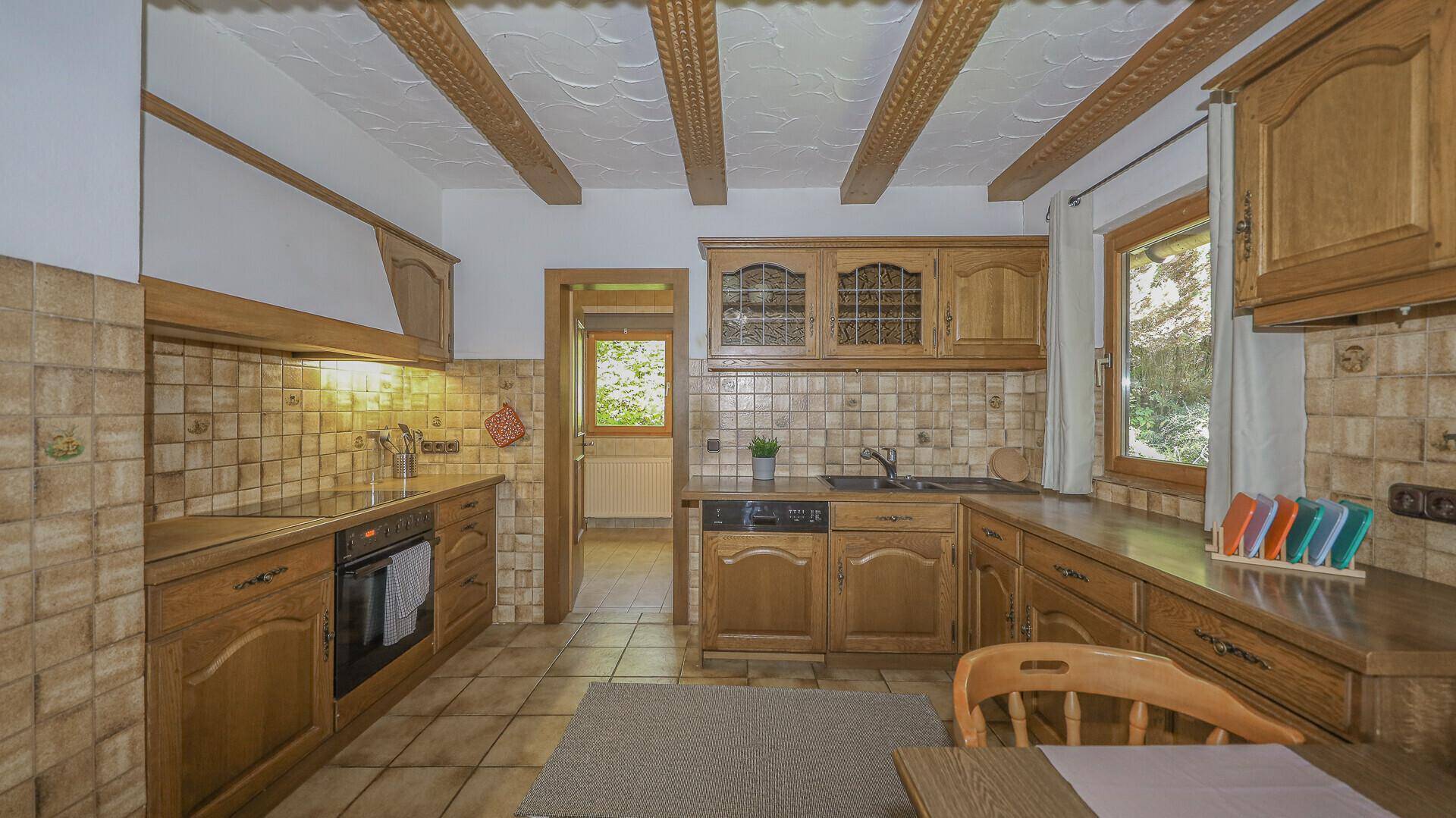 Traditionelle Holzküche mit gefliestem Spritzschutz, Holzarbeitsplatten und Einbaugeräten.