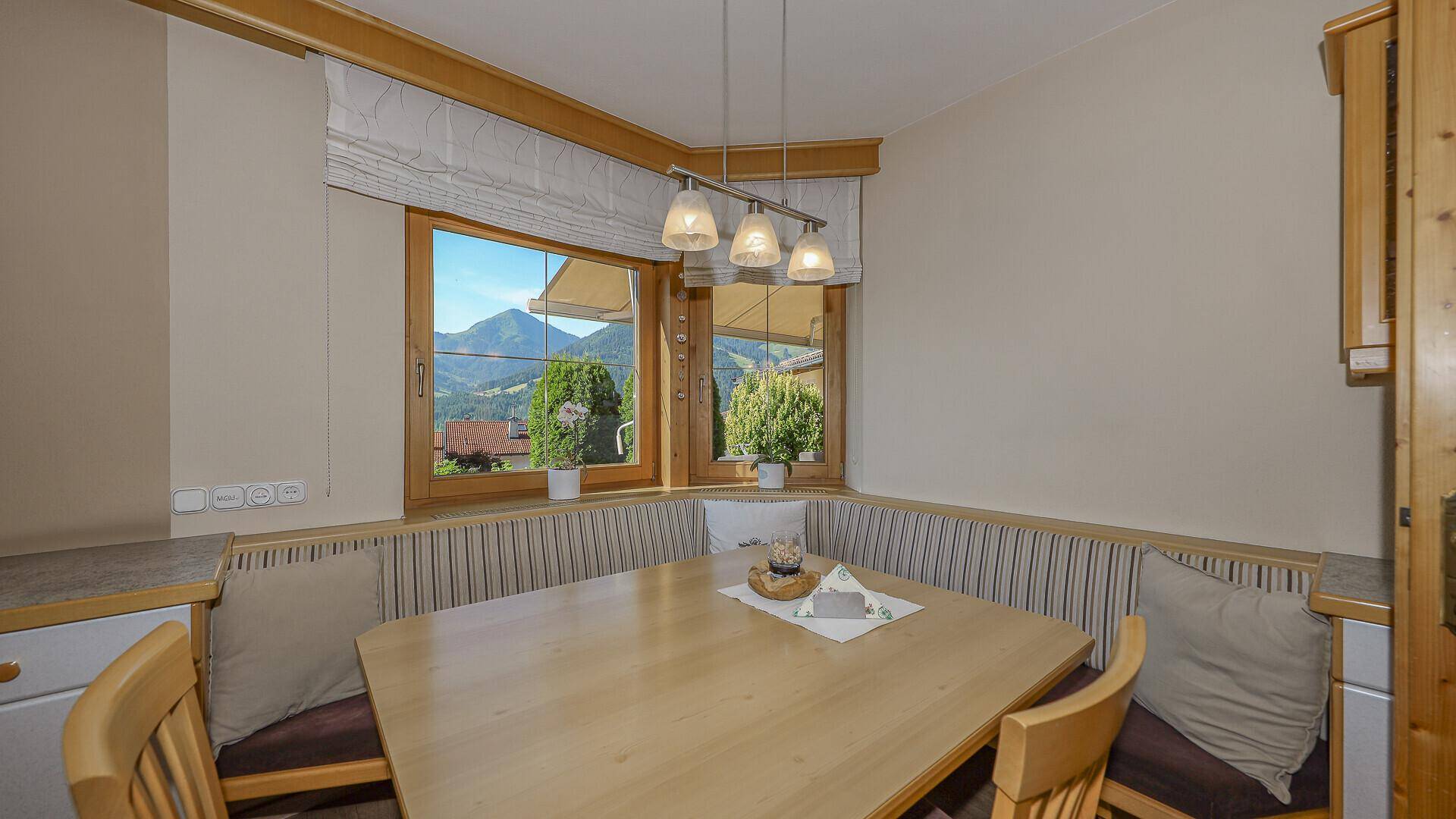 Gemütlicher Essbereich in der Küche mit Eckbank und Bergblick durch das Fenster.