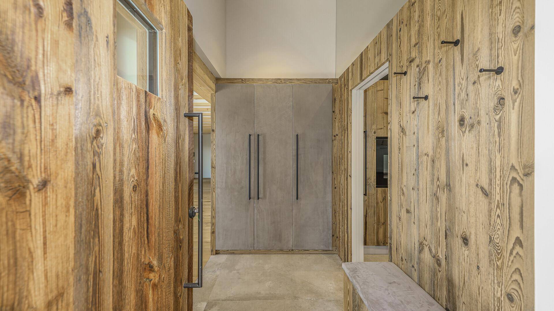 Eingangsbereich mit Holzwänden, Einbauschränken und Garderobe im alpinen Stil.
