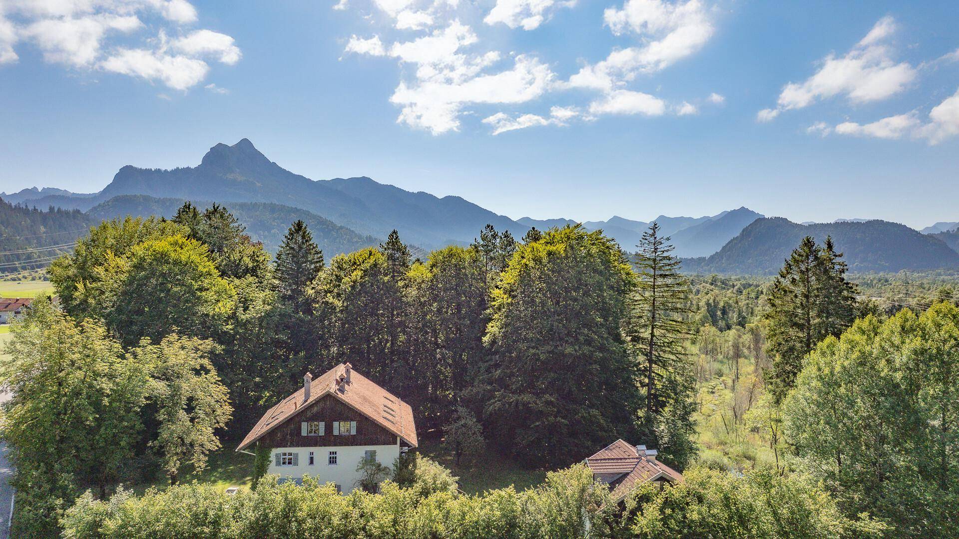 Weitläufige Luftaufnahme des Anwesens, eingebettet in grüne Wälder mit beeindruckendem Bergblick.