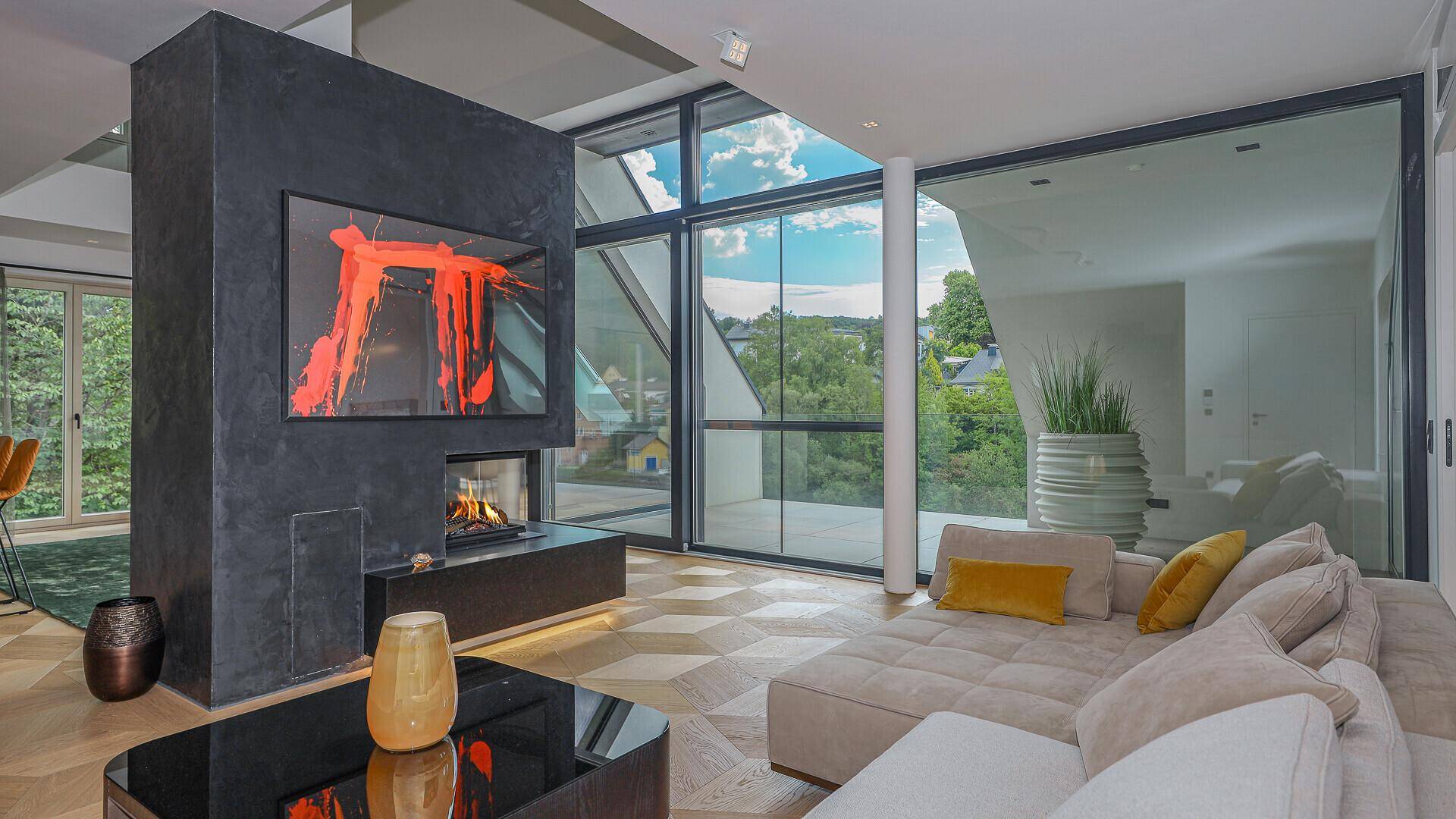 Gemütlicher Wohnbereich mit modernem Kamin, bequemer Couch und weitem Ausblick durch große Fenster.