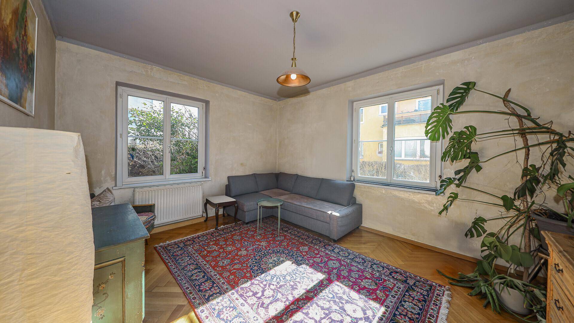 Wohnzimmer mit zwei Fenstern, Parkettboden und traditionellem Orientteppich.