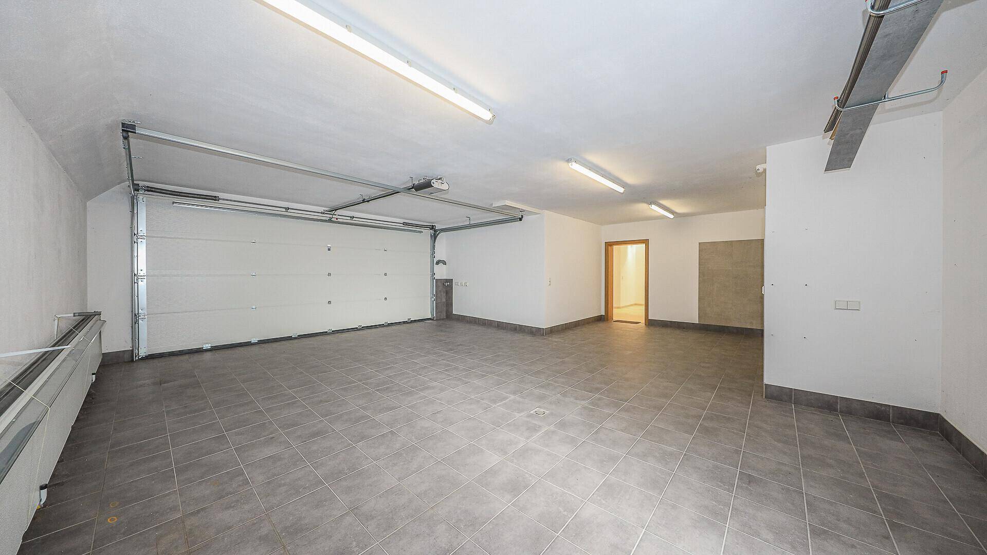 Geräumige Garage mit automatischem Tor und Fliesenboden.