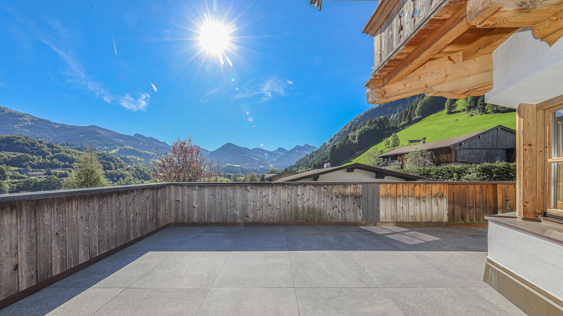 Große, sonnige Terrasse mit Fliesenboden und weitem Blick auf die umliegende Berglandschaft.