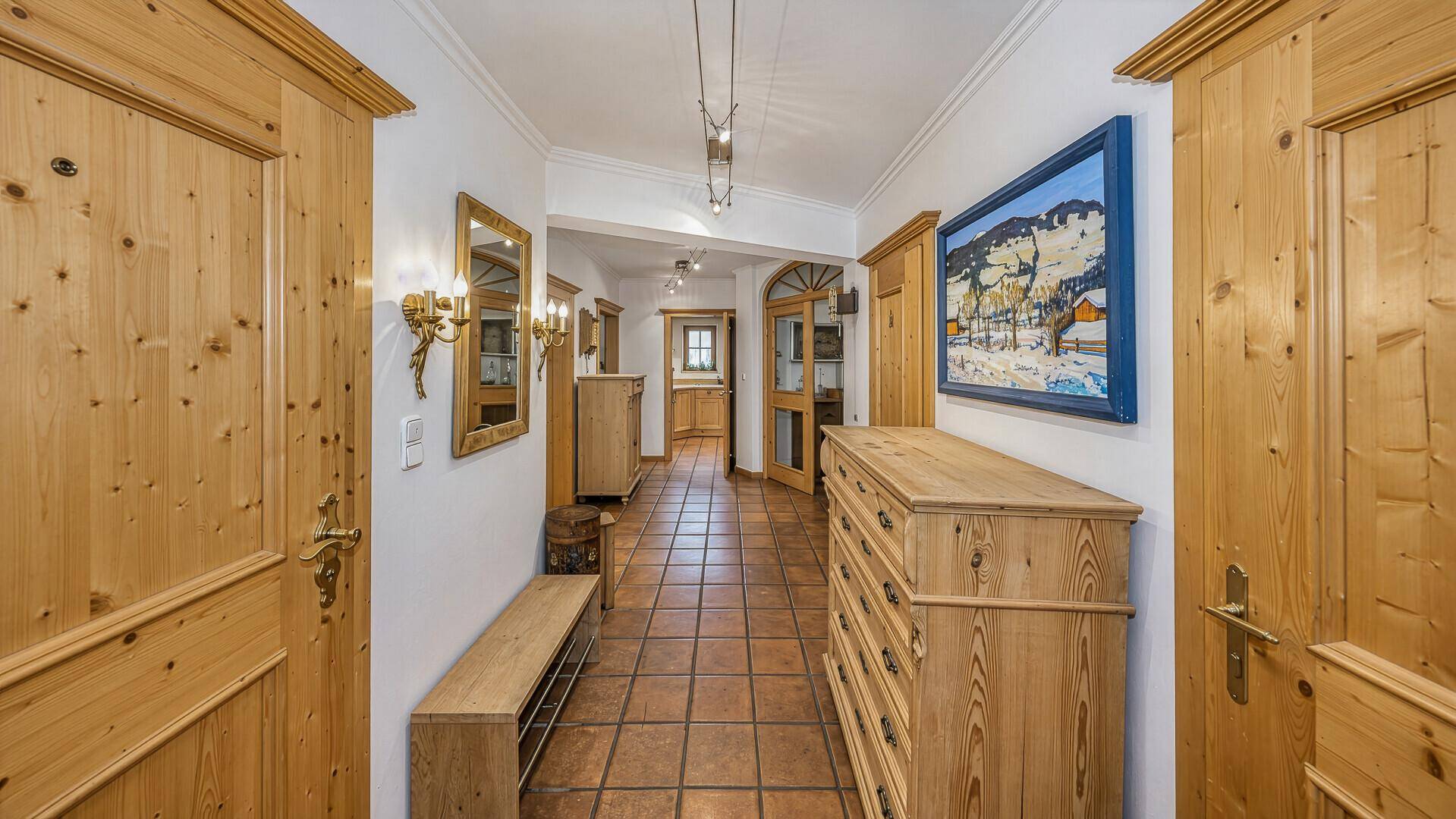 Geräumiger Flur mit traditionellen Holzmöbeln, Terrakotta-Fliesenboden und dekorativer Wandkunst.