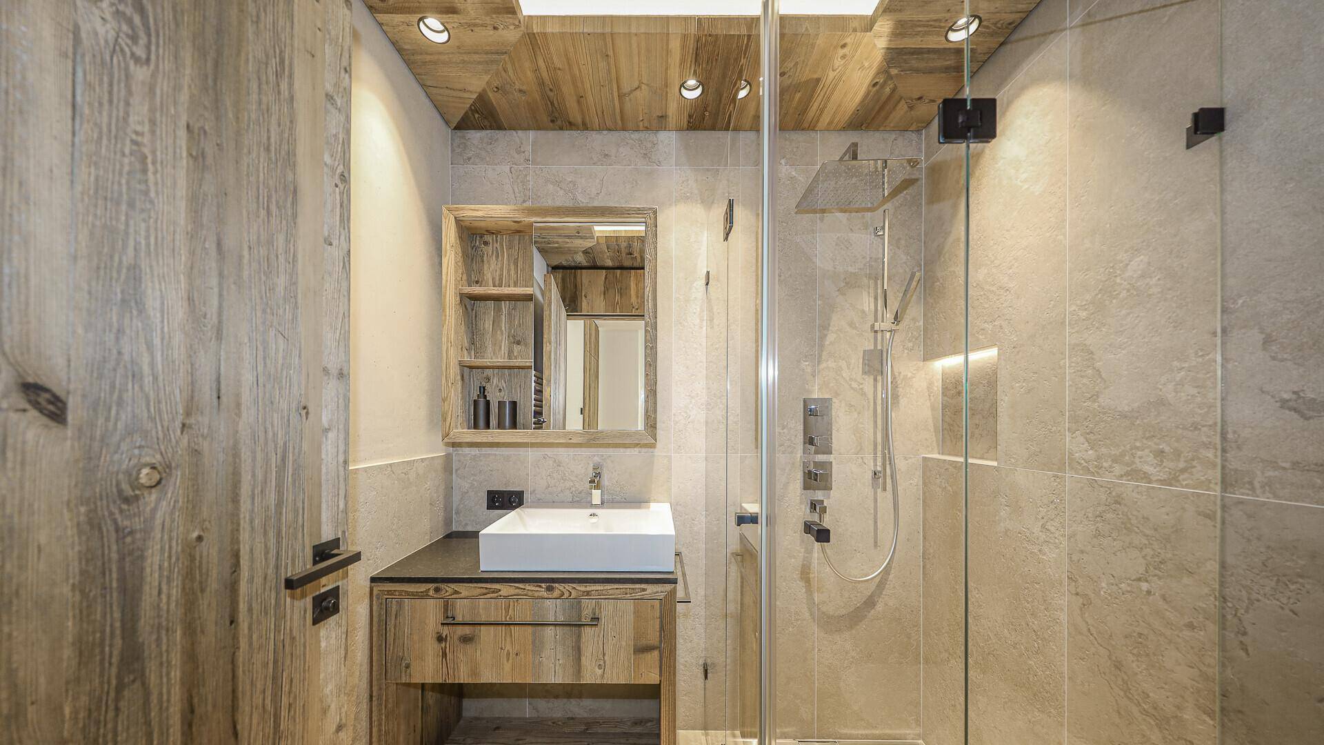 Modernes Badezimmer mit begehbarer Dusche, Einzelwaschbecken und Holzdetails.